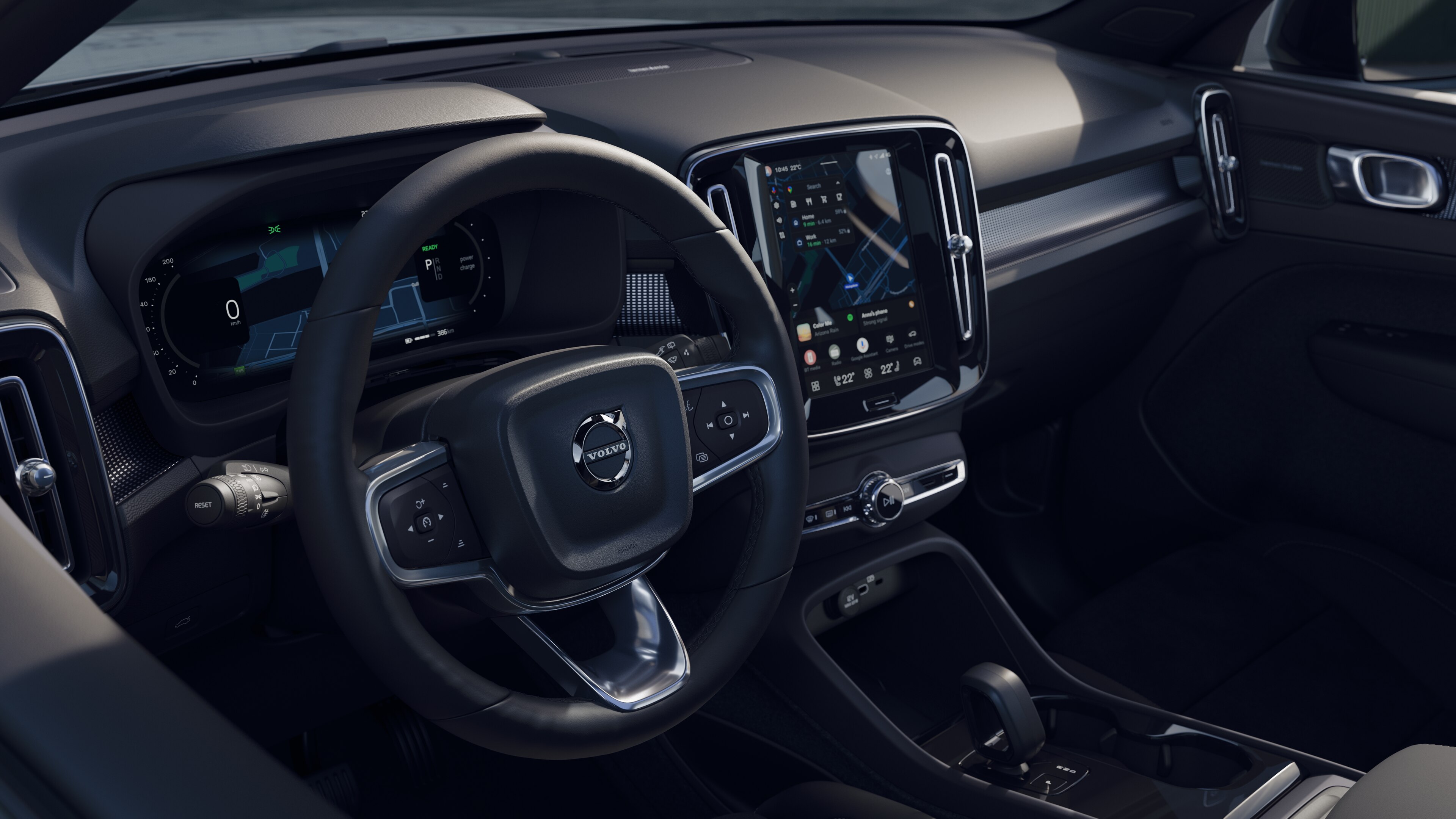 Intérieur d’une Volvo montrant le tableau de bord, le volant et la console centrale avec affichage numérique sur fond de route ouverte.