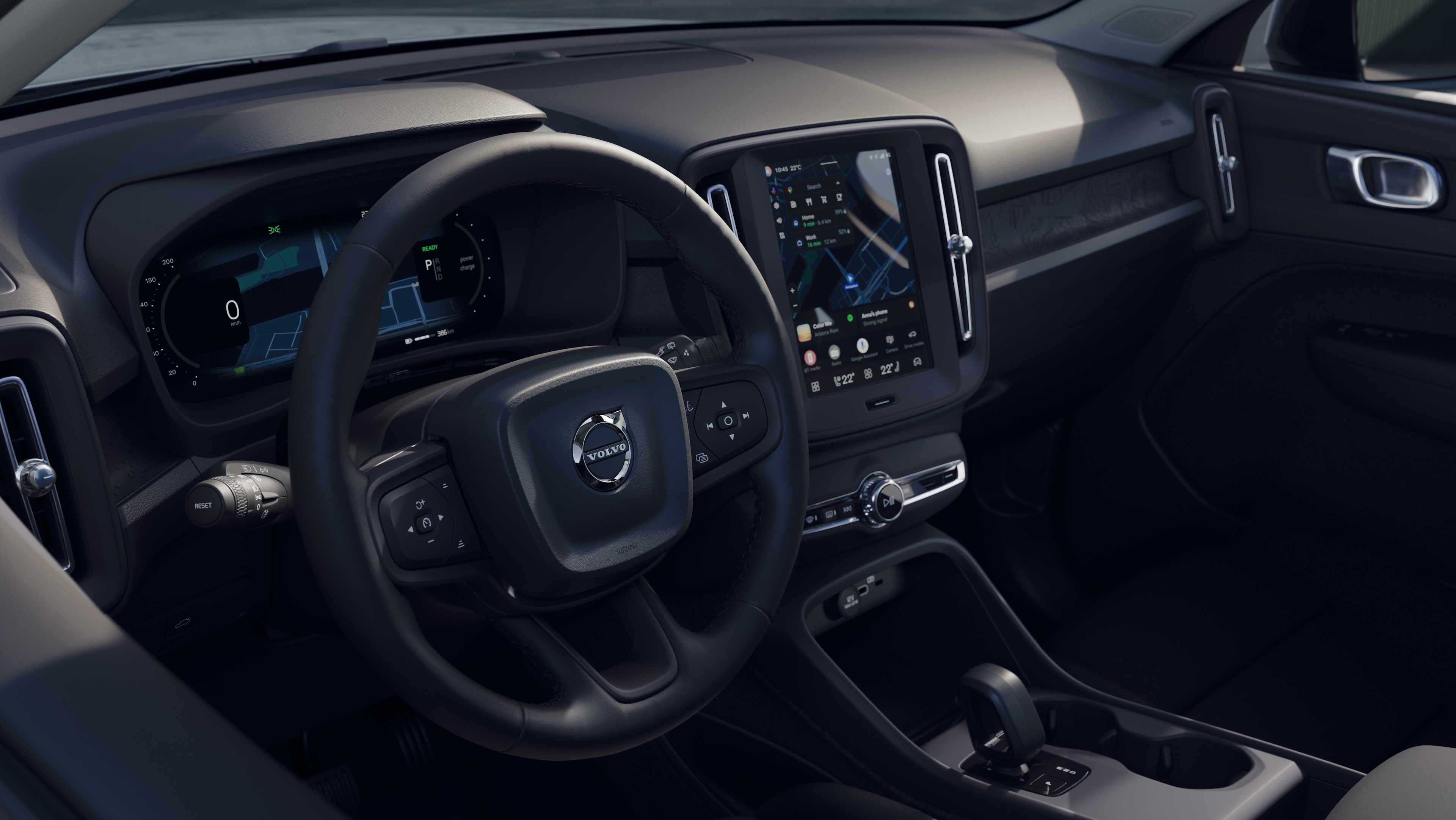 Intérieur d’une Volvo montrant le tableau de bord, le volant et la console centrale avec affichage numérique sur fond de route ouverte.