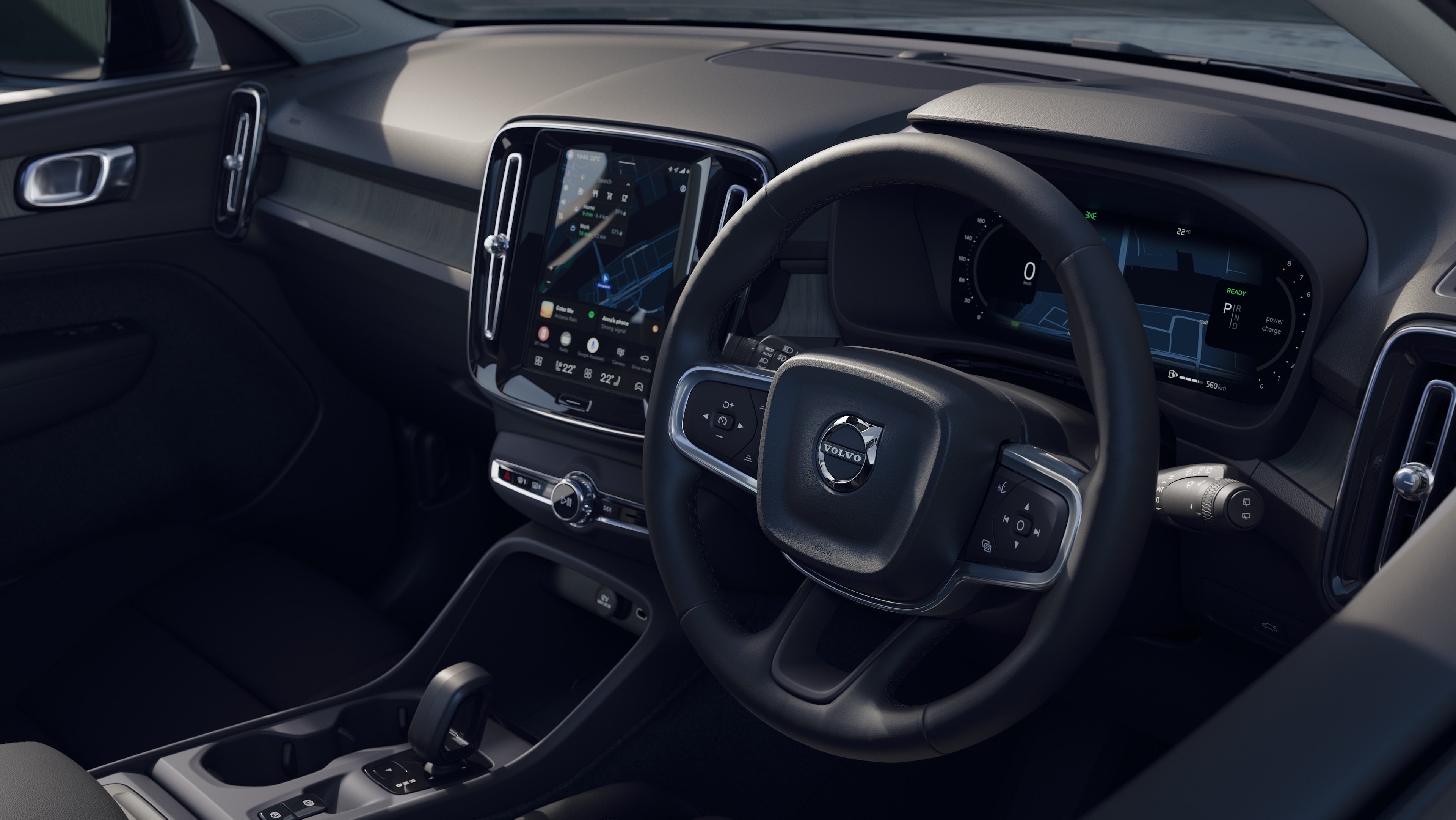 Volvo car interior showing dashboard, steering wheel, and center console with digital display in an open road background.