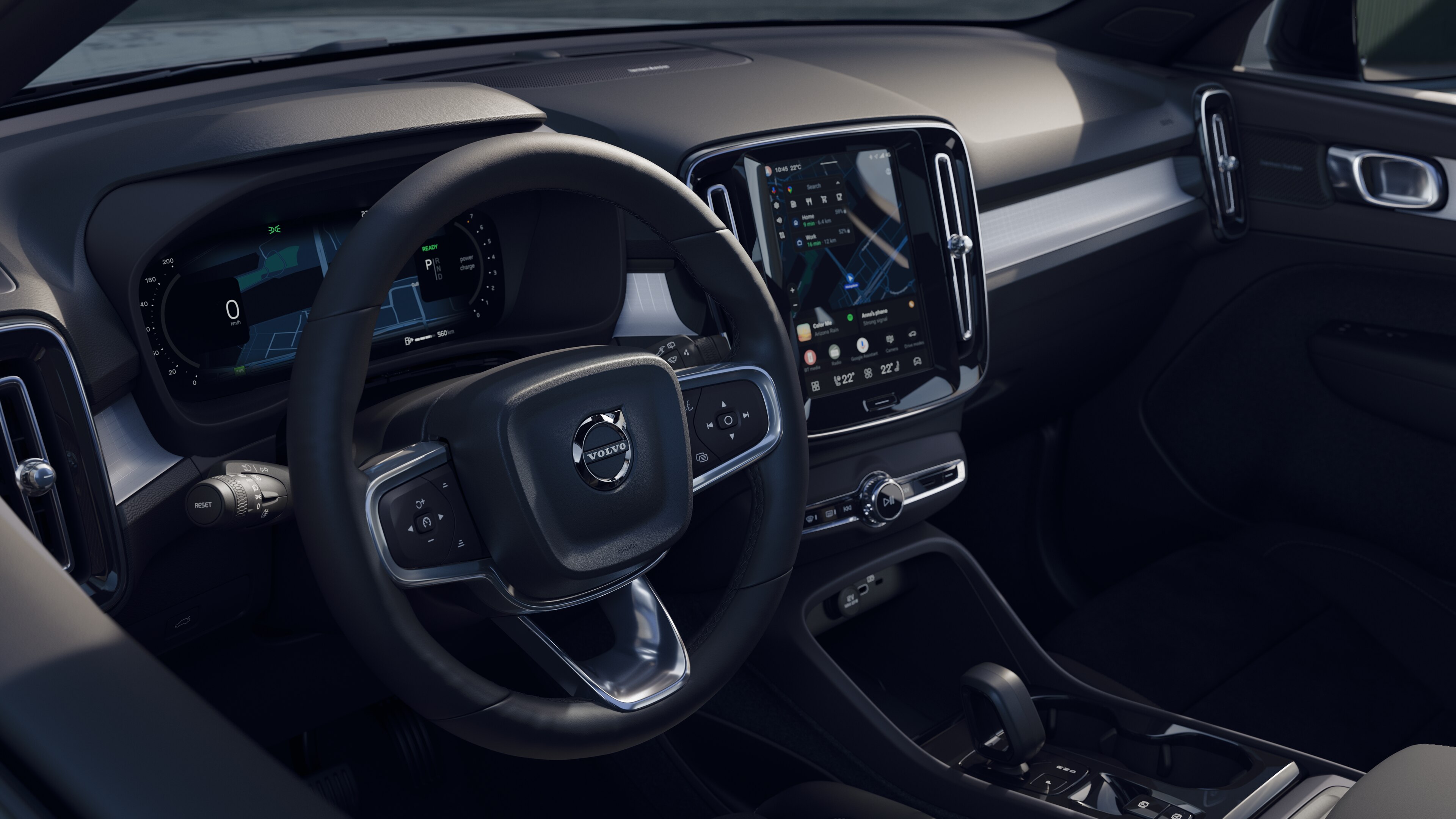 Wnętrze samochodu Volvo z deską rozdzielczą, kierownicą i konsolą środkową z cyfrowym wyświetlaczem na otwartym tle drogi.