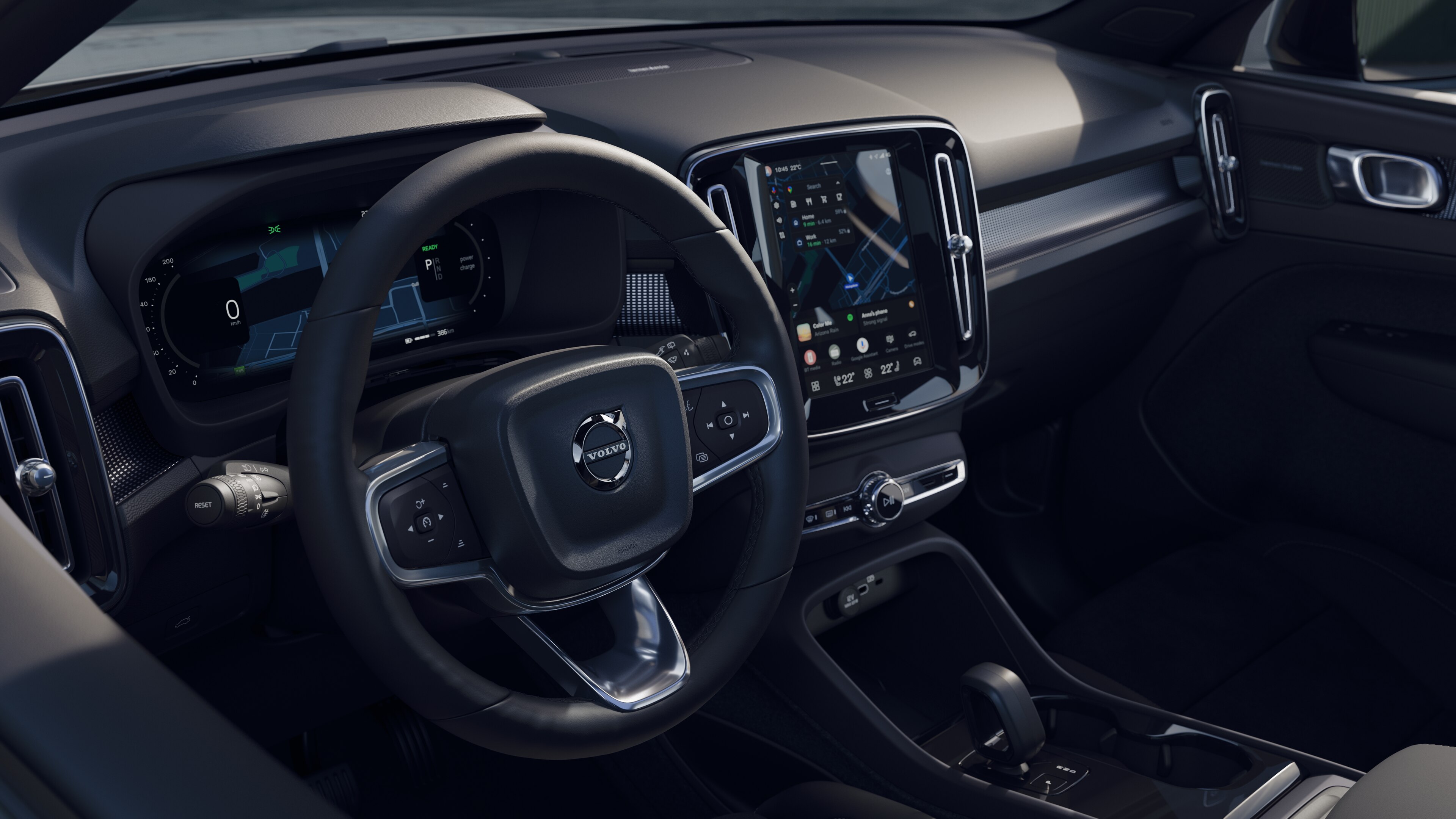 Interno di un'auto Volvo che mostra cruscotto, volante e console centrale con display digitale sullo sfondo di una strada aperta.