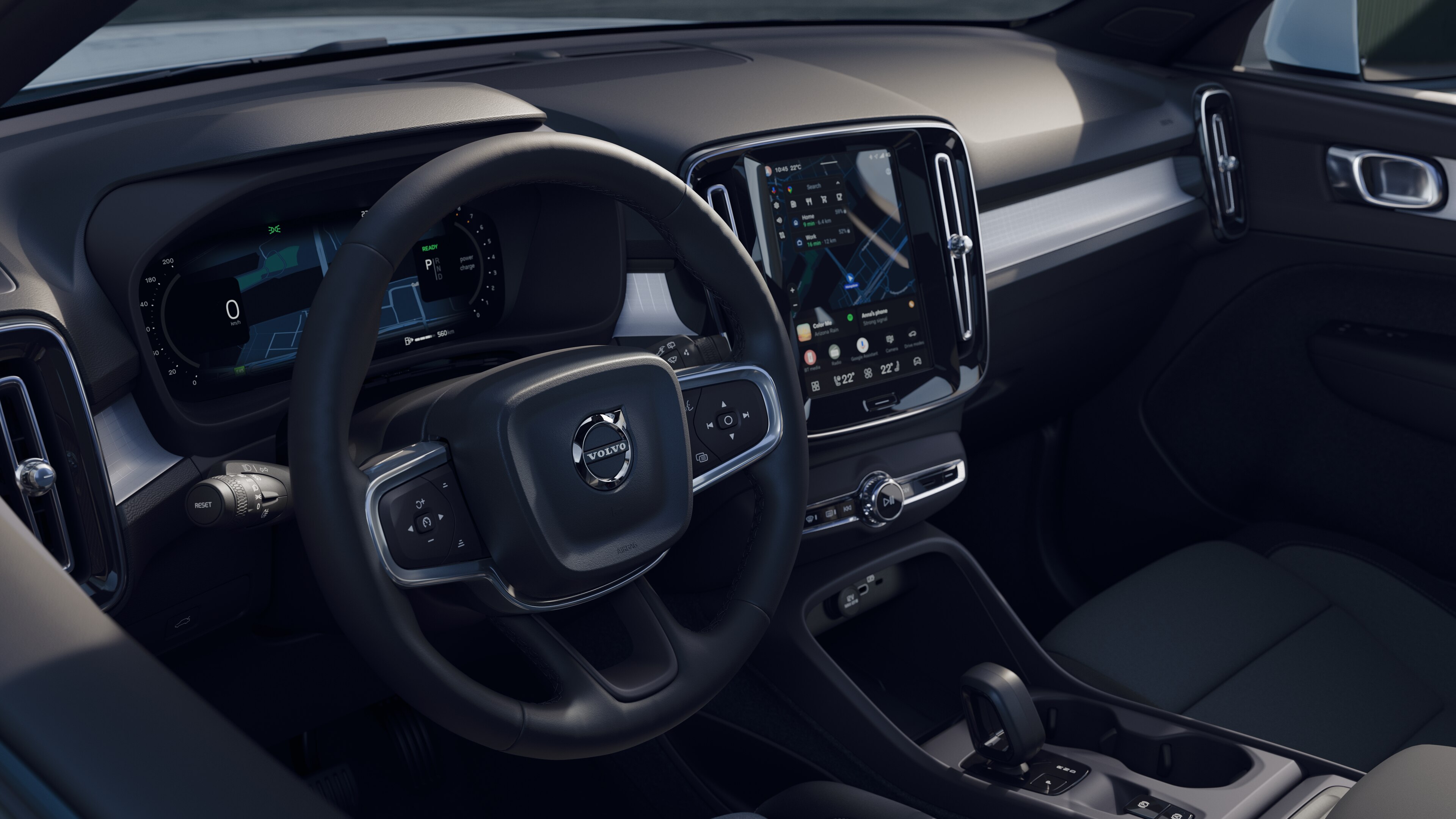 Wnętrze samochodu Volvo z deską rozdzielczą, kierownicą i konsolą środkową z cyfrowym wyświetlaczem na otwartym tle drogi.