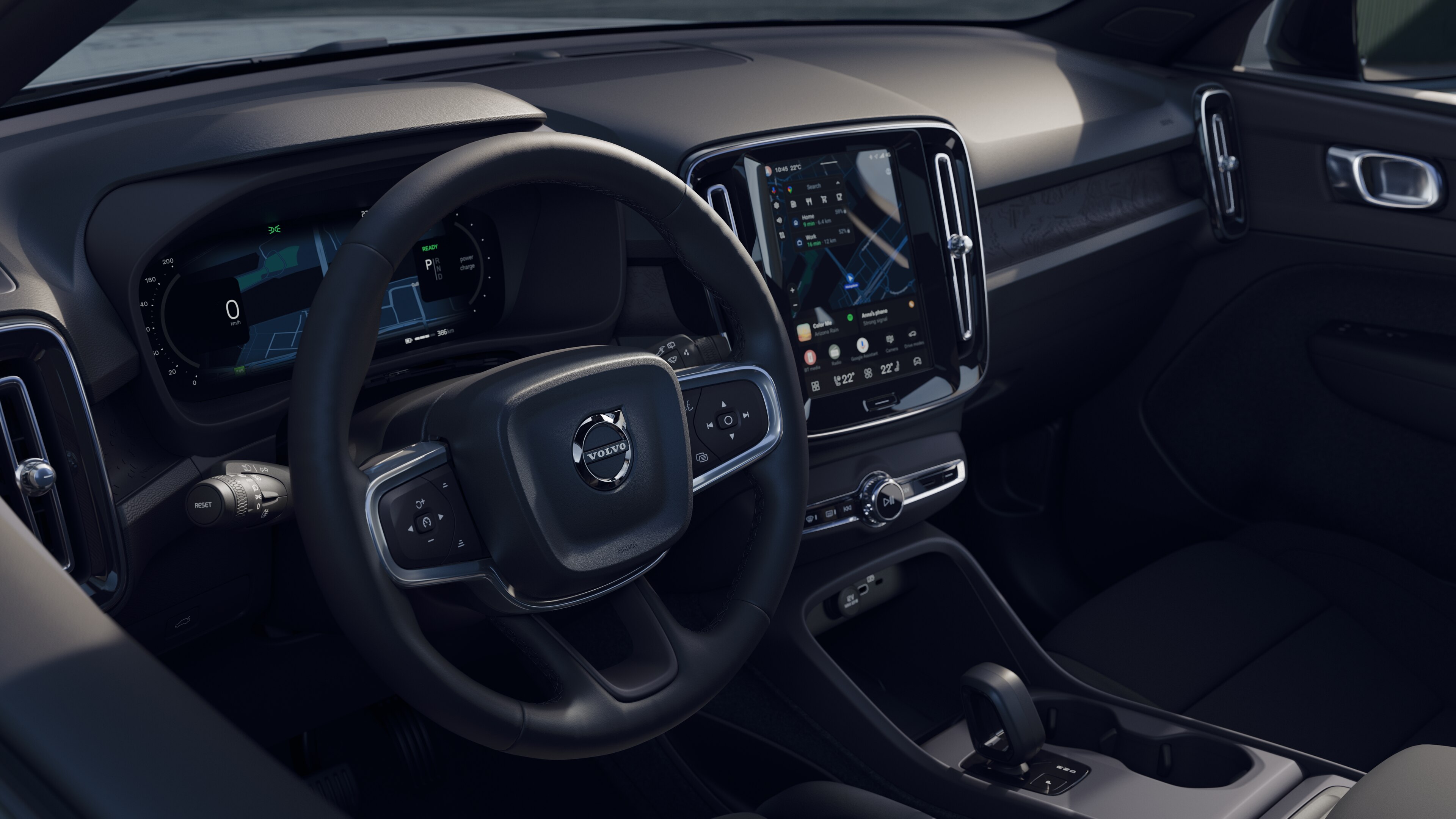 Het interieur van een Volvo met dashboard, stuur en middenconsole met digitaal display op een open wegachtergrond.