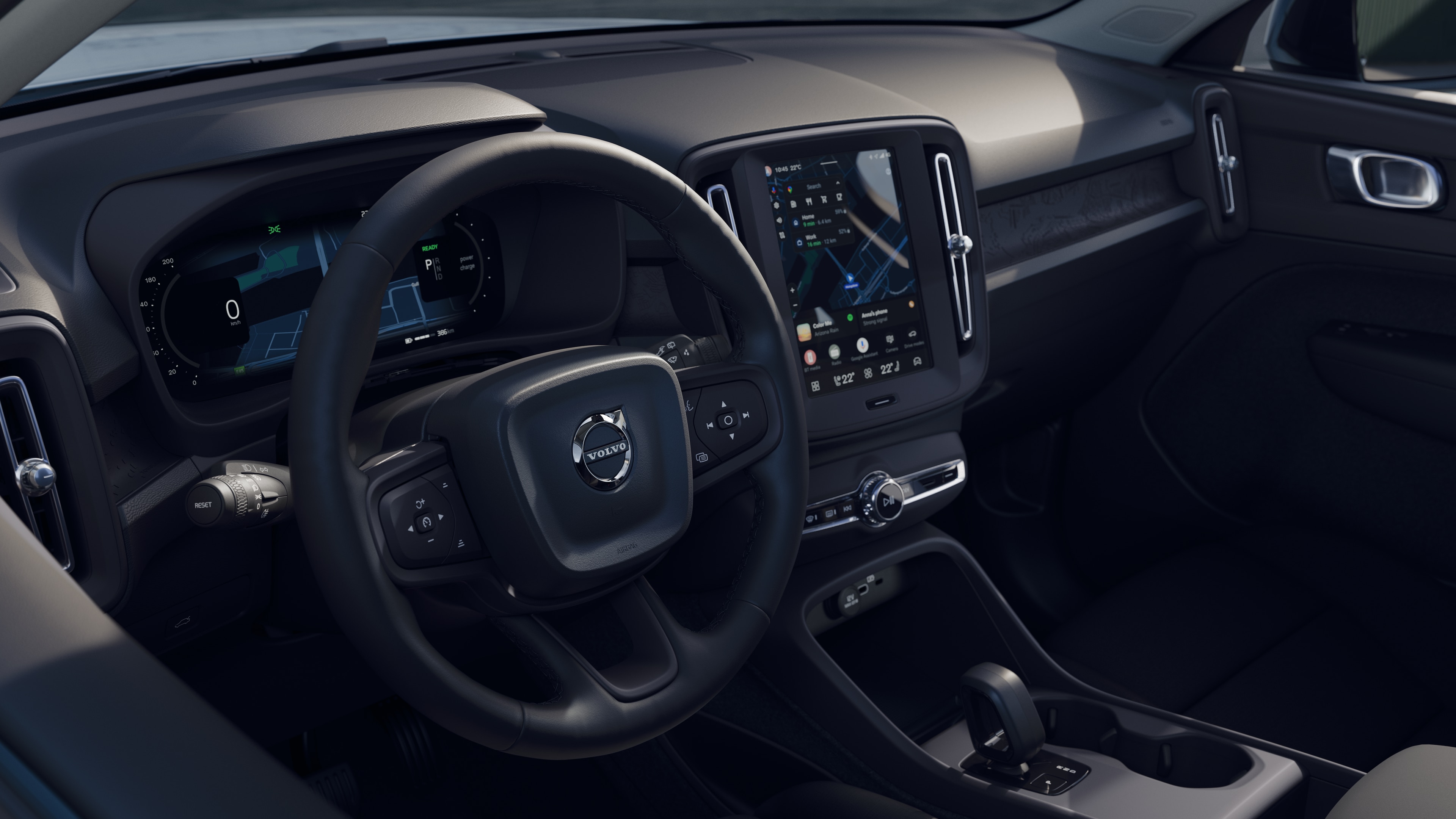 Wnętrze samochodu Volvo z deską rozdzielczą, kierownicą i konsolą środkową z cyfrowym wyświetlaczem na otwartym tle drogi.