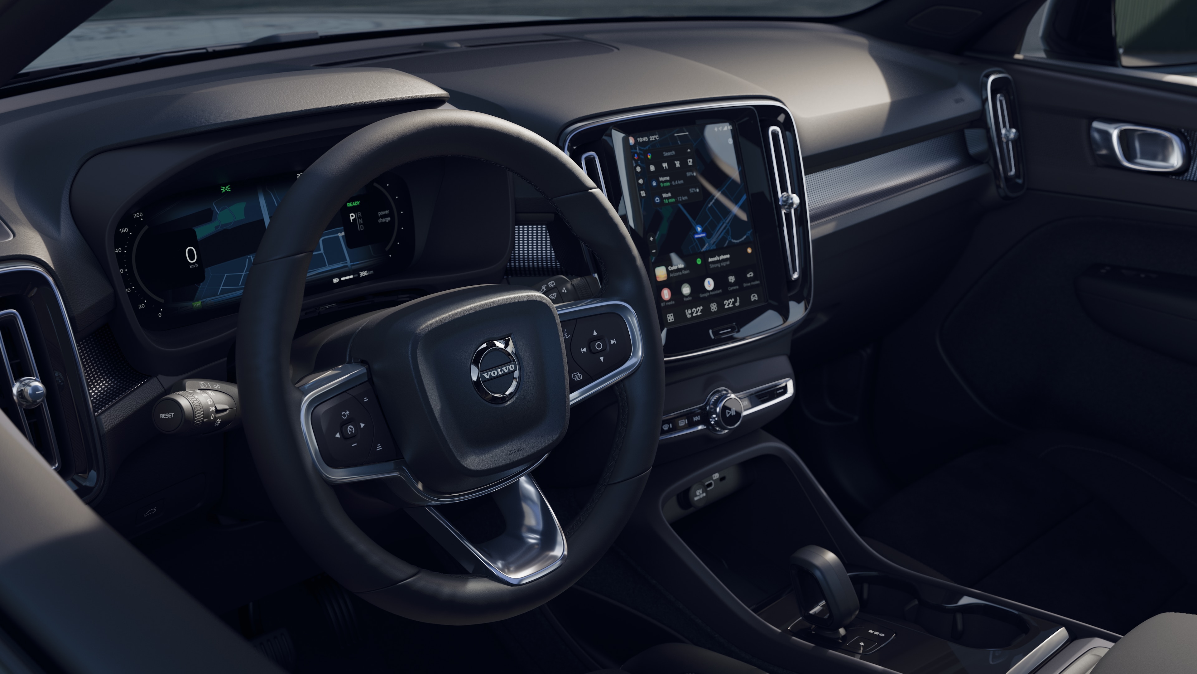 Interior del vehículo Volvo que muestra el salpicadero, el volante y la consola central con pantalla digital en un fondo de carretera abierta.