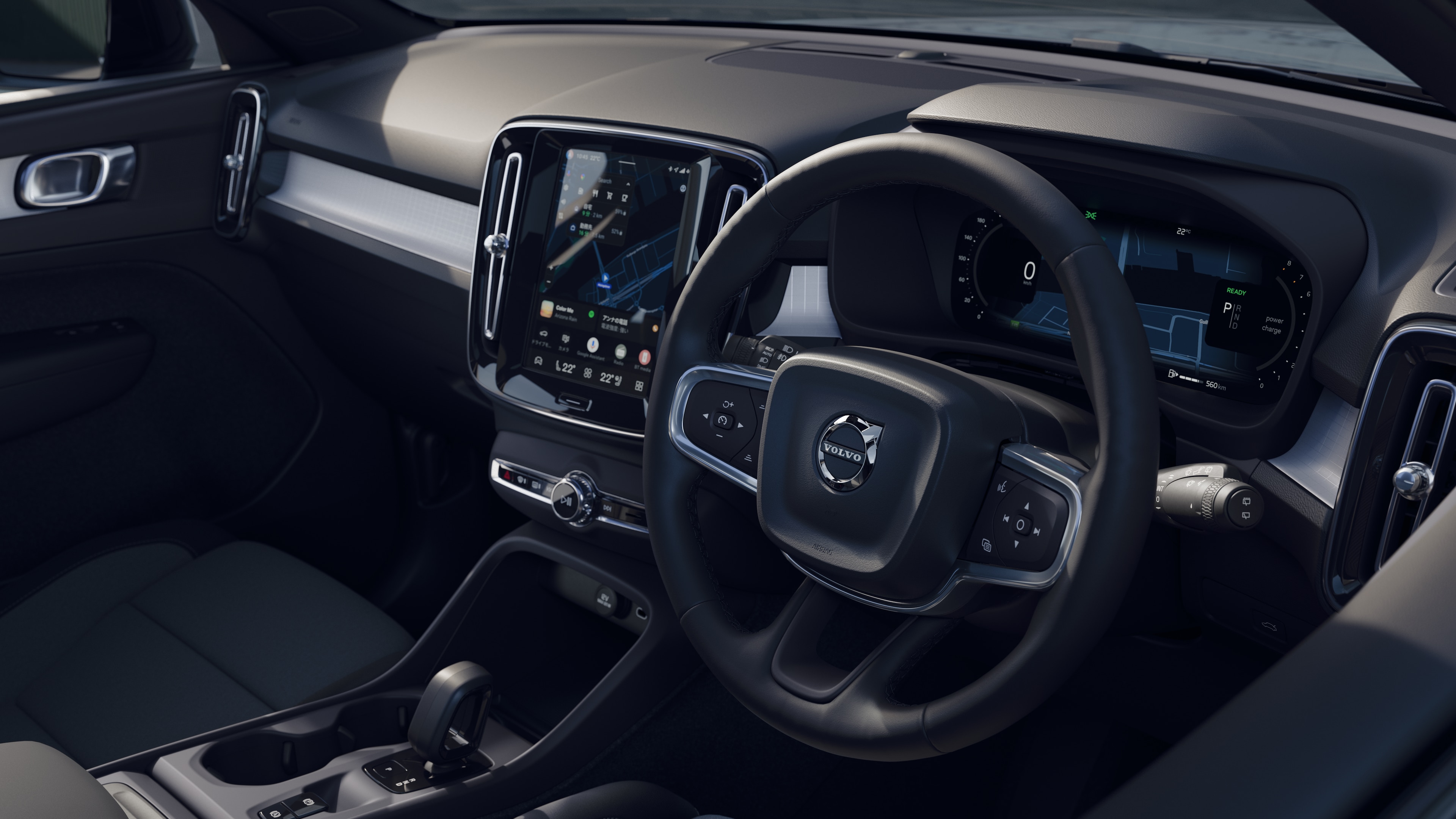 開けた路面を背景にダッシュボード、ステアリングホイール、センターコンソールをデジタルディスプレイで捉えたボルボ車のインテリア。