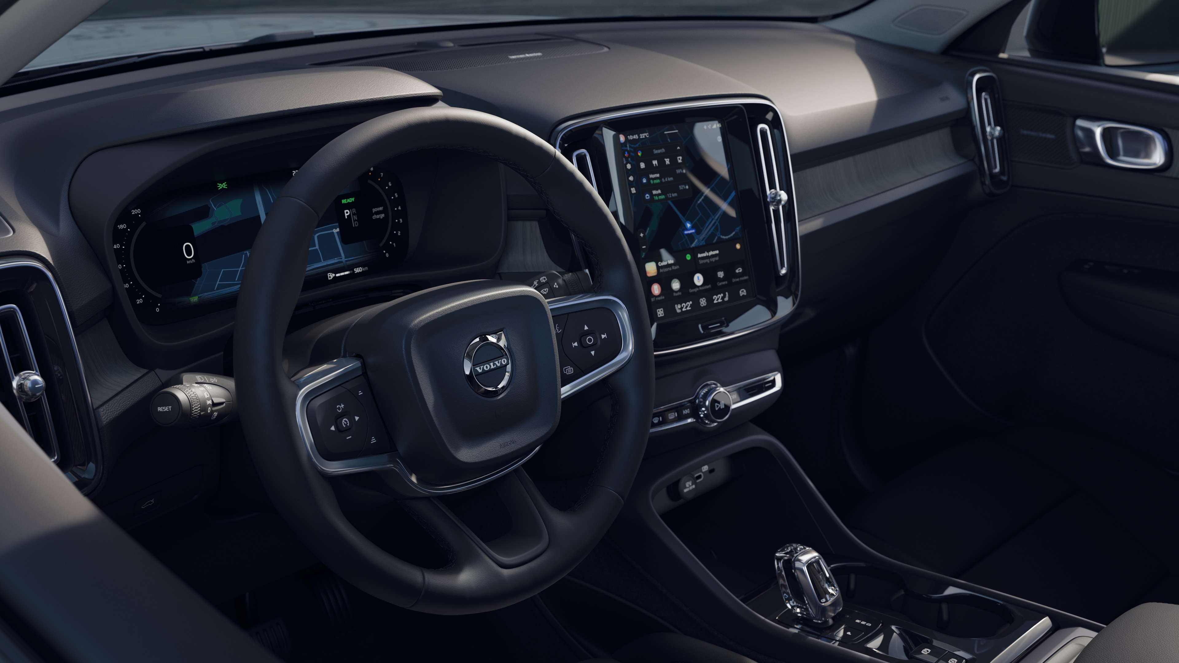 Intérieur d’une Volvo montrant le tableau de bord, le volant et la console centrale avec affichage numérique sur un fond de route dégagée.