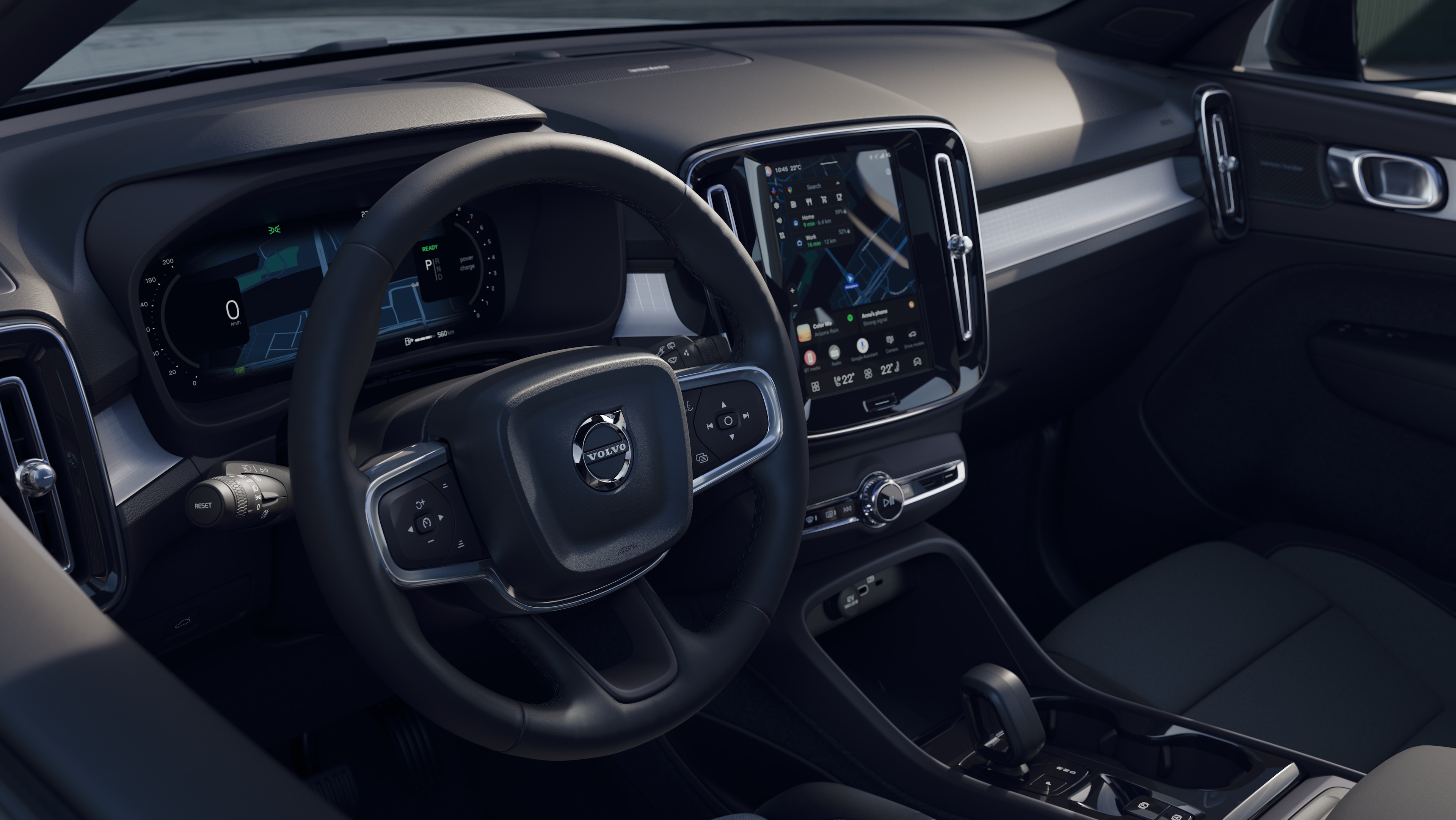 Intérieur d’une Volvo montrant le tableau de bord, le volant et la console centrale avec affichage numérique sur fond de route ouverte.