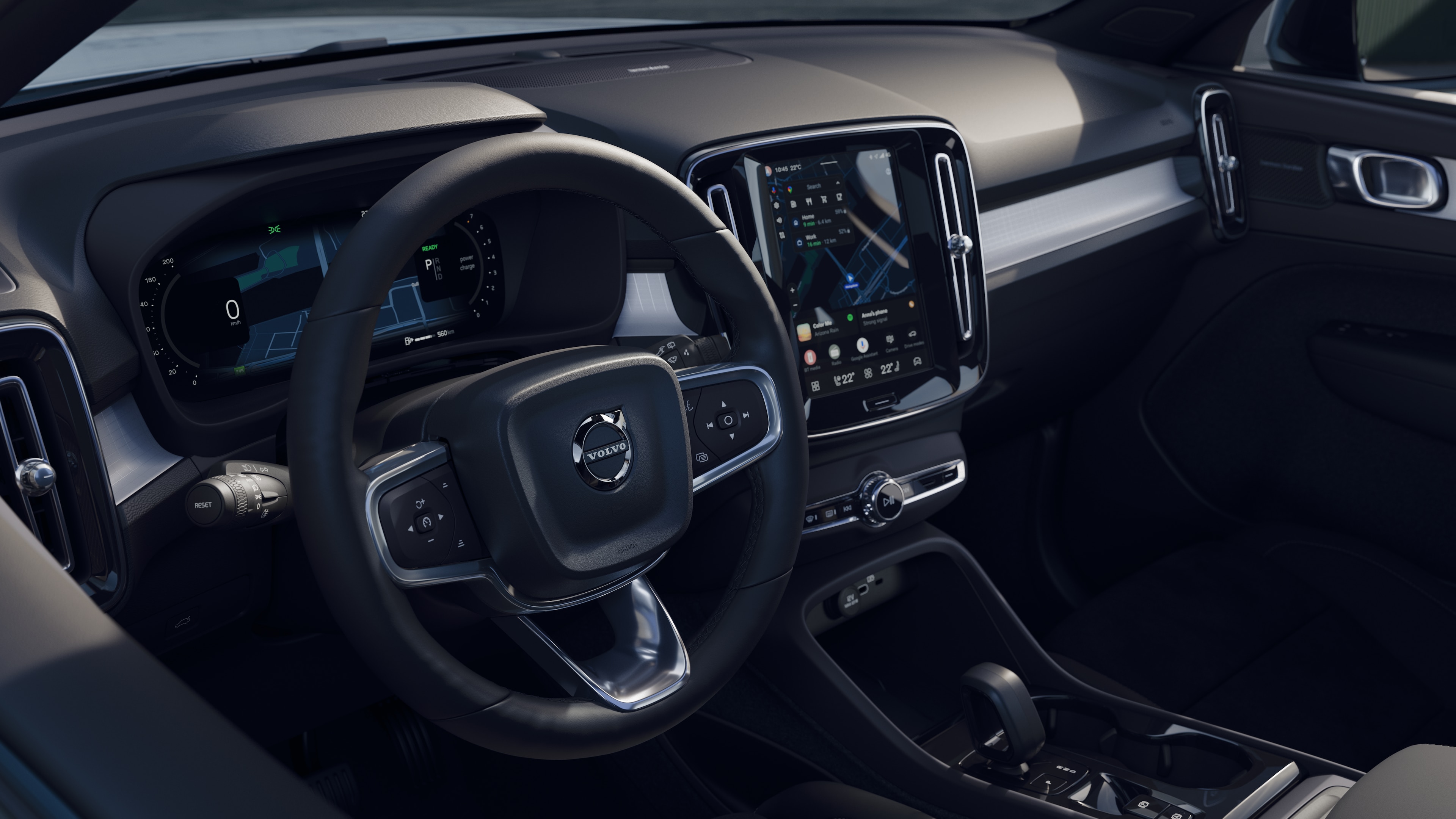 Wnętrze samochodu Volvo z deską rozdzielczą, kierownicą i konsolą środkową z cyfrowym wyświetlaczem na otwartym tle drogi.