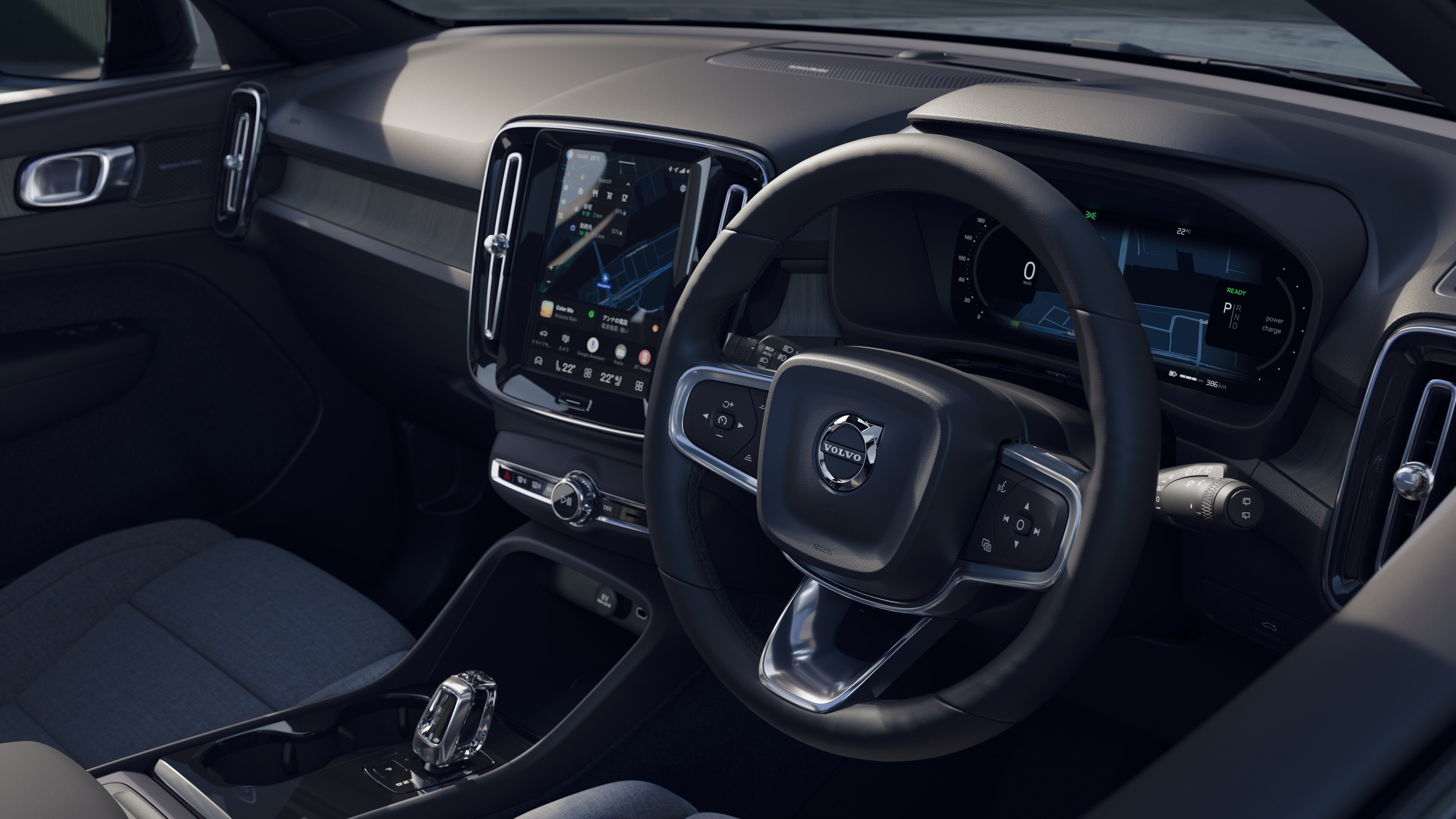 開けた路面を背景にダッシュボード、ステアリングホイール、センターコンソールをデジタルディスプレイで捉えたボルボ車のインテリア。