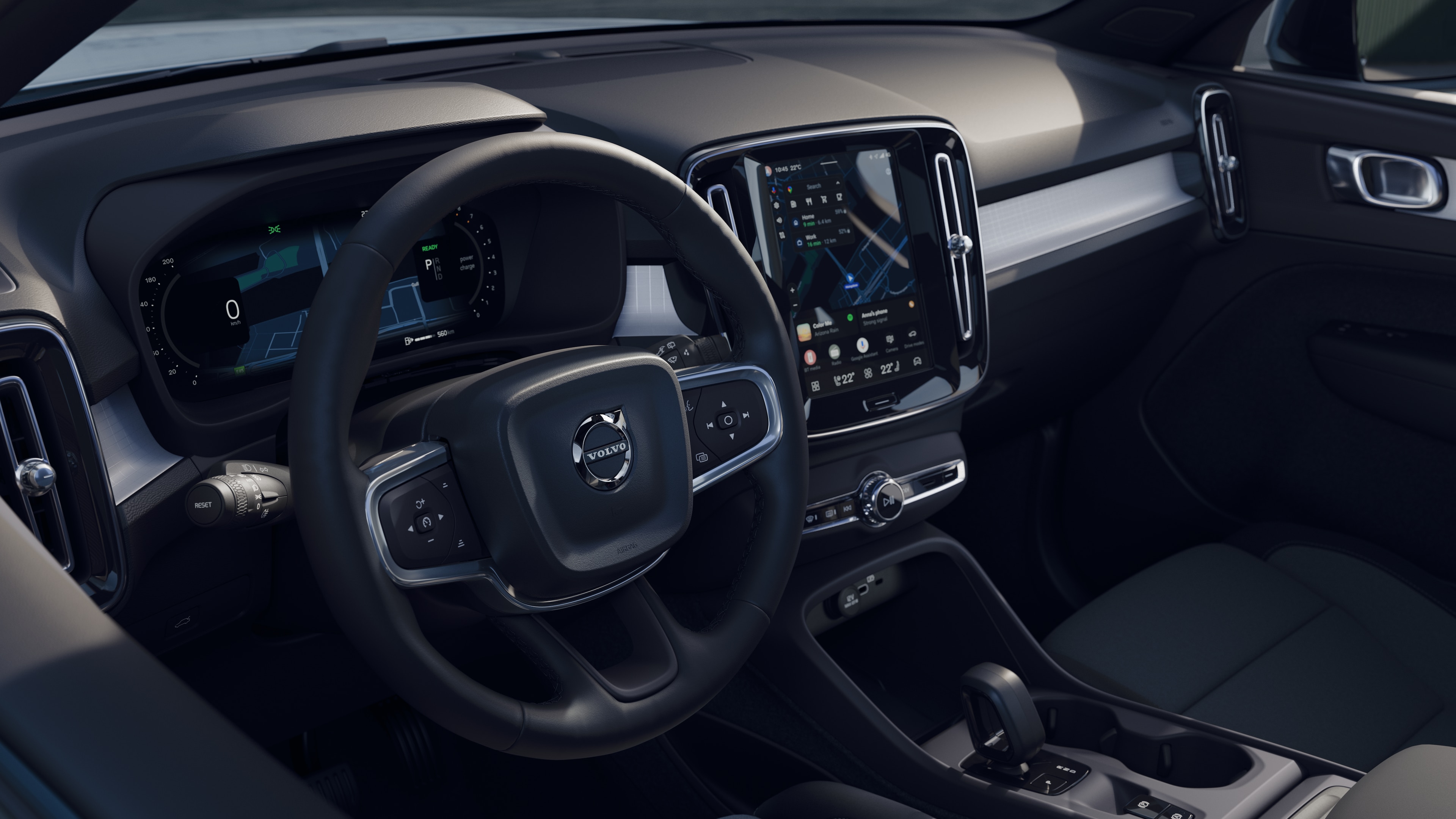 L’intérieur d’une Volvo montrant le tableau de bord, le volant et la console centrale avec affichage numérique sur un fond de route ouverte.