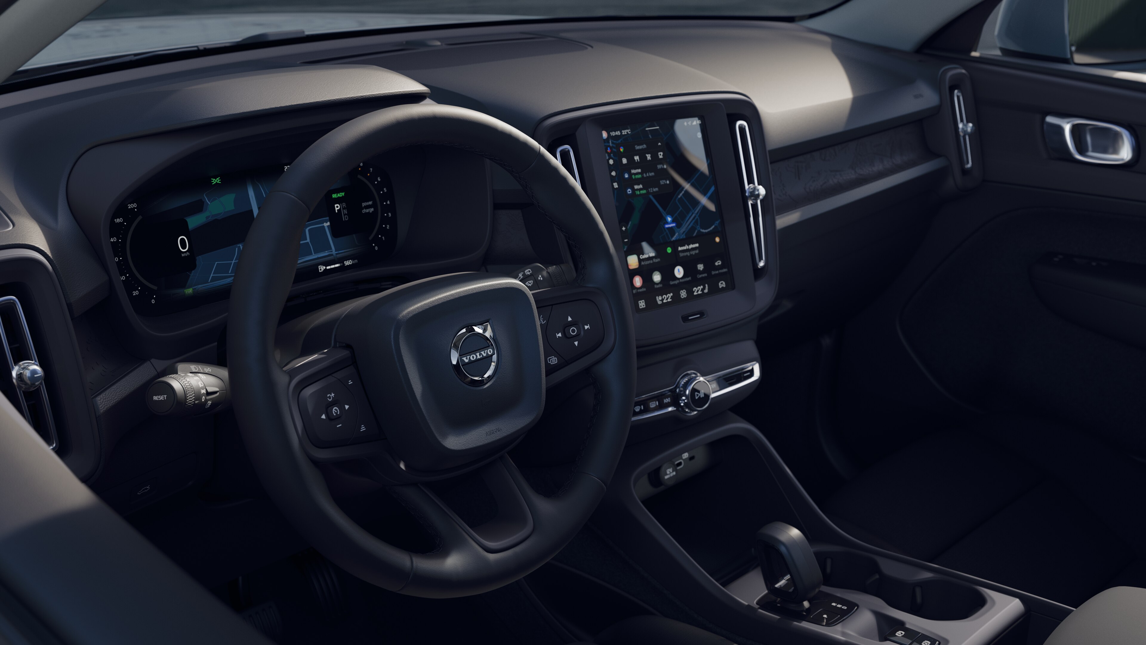 Intérieur d’une Volvo montrant le tableau de bord, le volant et la console centrale avec affichage numérique sur fond de route ouverte.