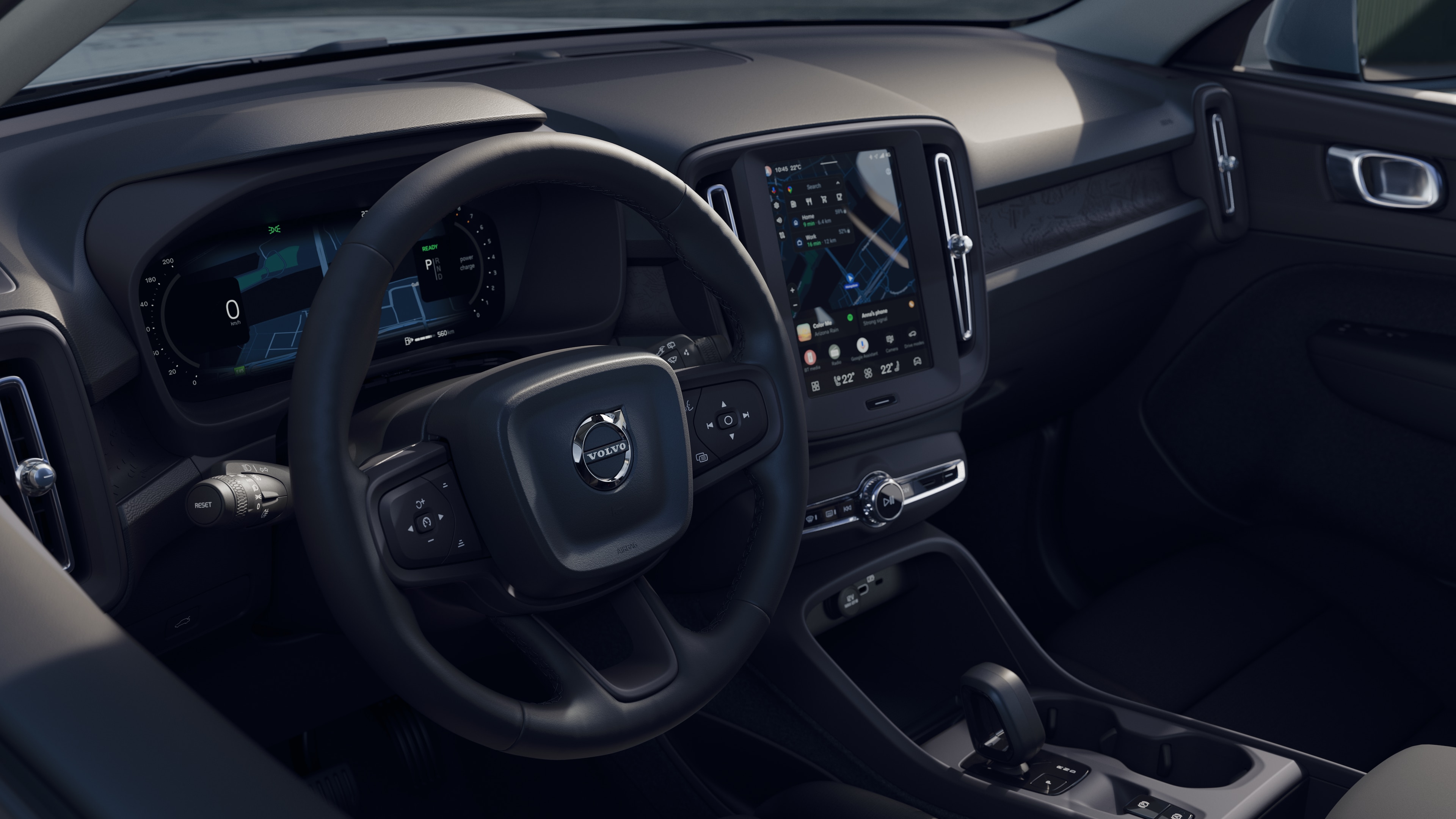 Intérieur d’une Volvo montrant le tableau de bord, le volant et la console centrale avec affichage numérique sur fond de route ouverte.