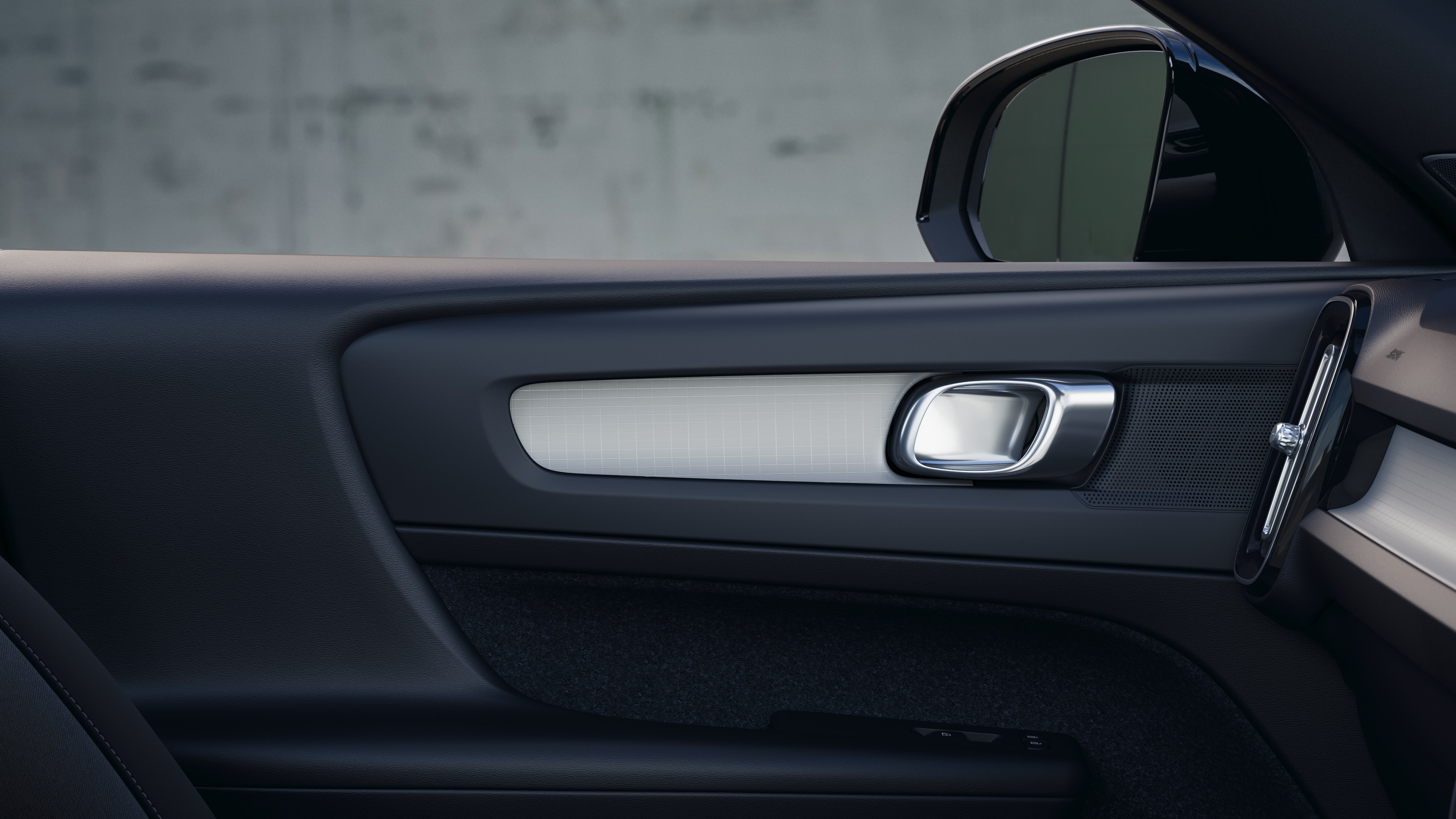 簡素なスタジオを背景に、フロントとリアの助手席、ステアリングホイール、ダッシュボード、センターコンソールを収めたボルボ車のインテリア。