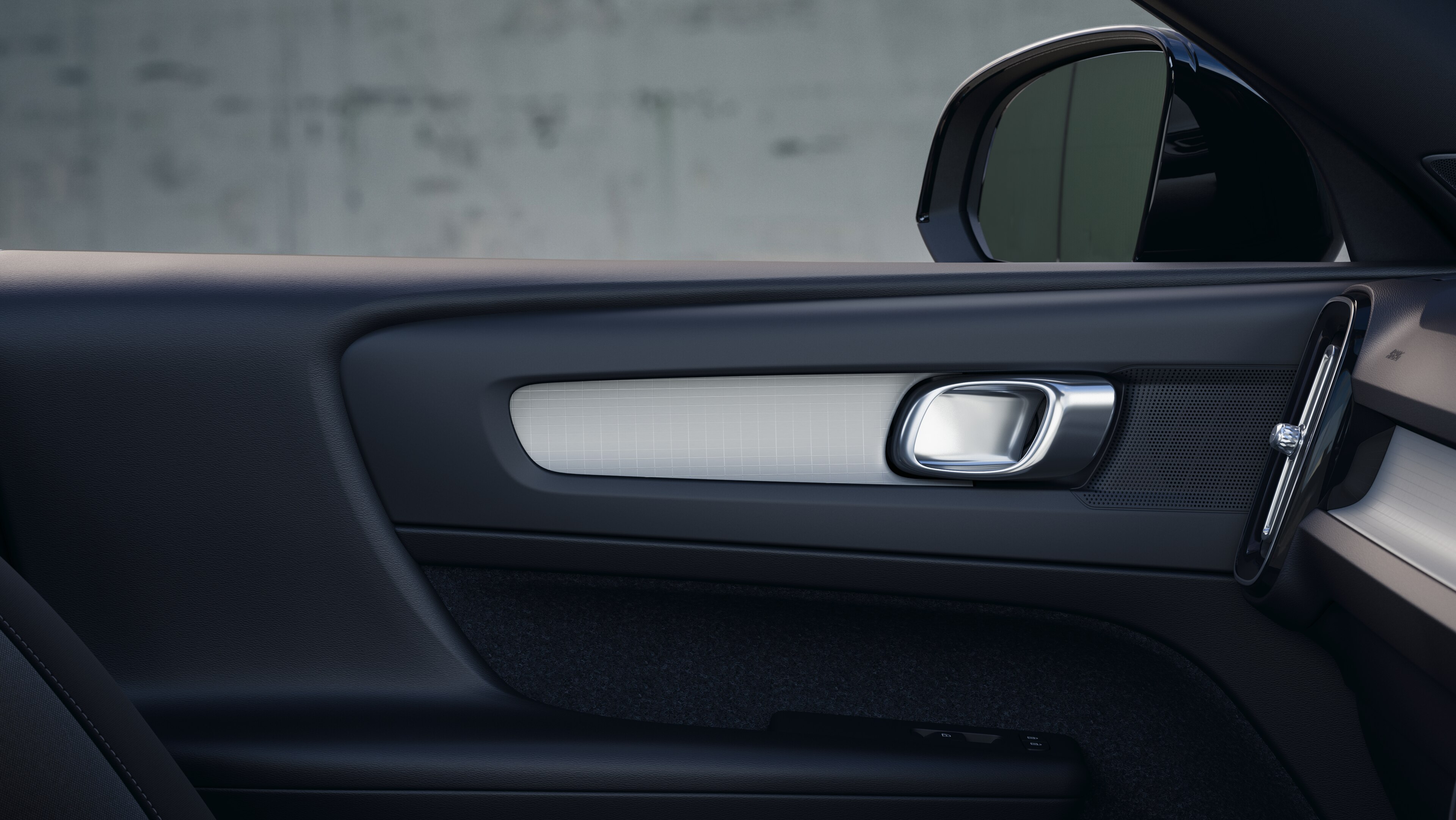 簡素なスタジオを背景に、フロントとリアの助手席、ステアリングホイール、ダッシュボード、センターコンソールを収めたボルボ車のインテリア。