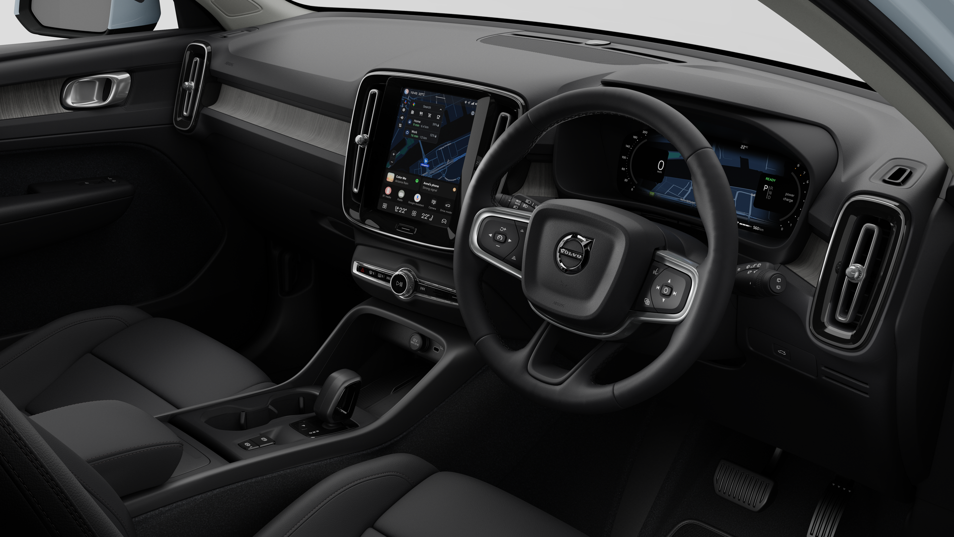 Interior view of a Volvo car showing the dashboard, steering wheel, center console, and digital display screen in a plain studio background.