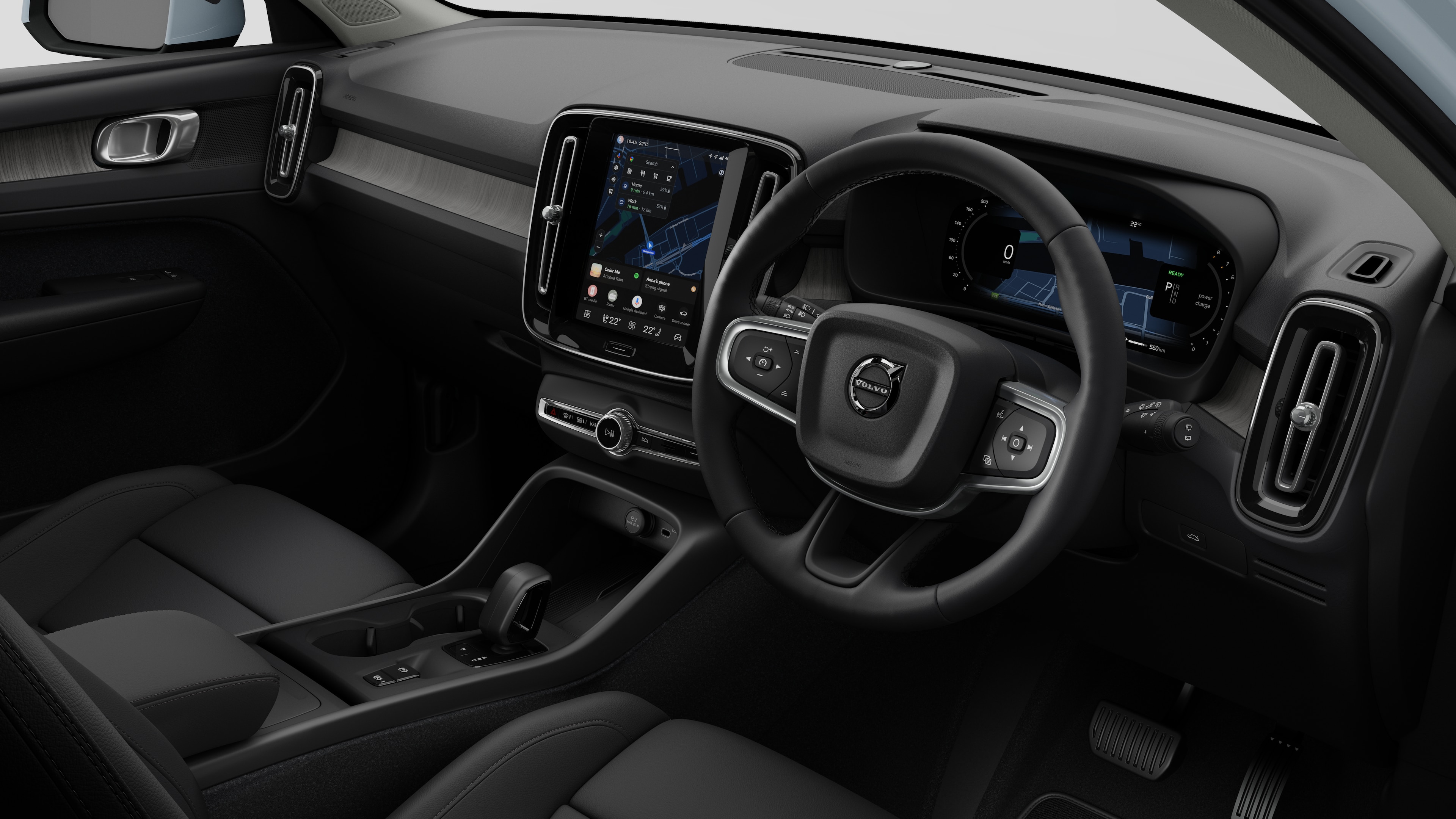 Interior view of a Volvo car showing the dashboard, steering wheel, center console, and digital display screen in a plain studio background.