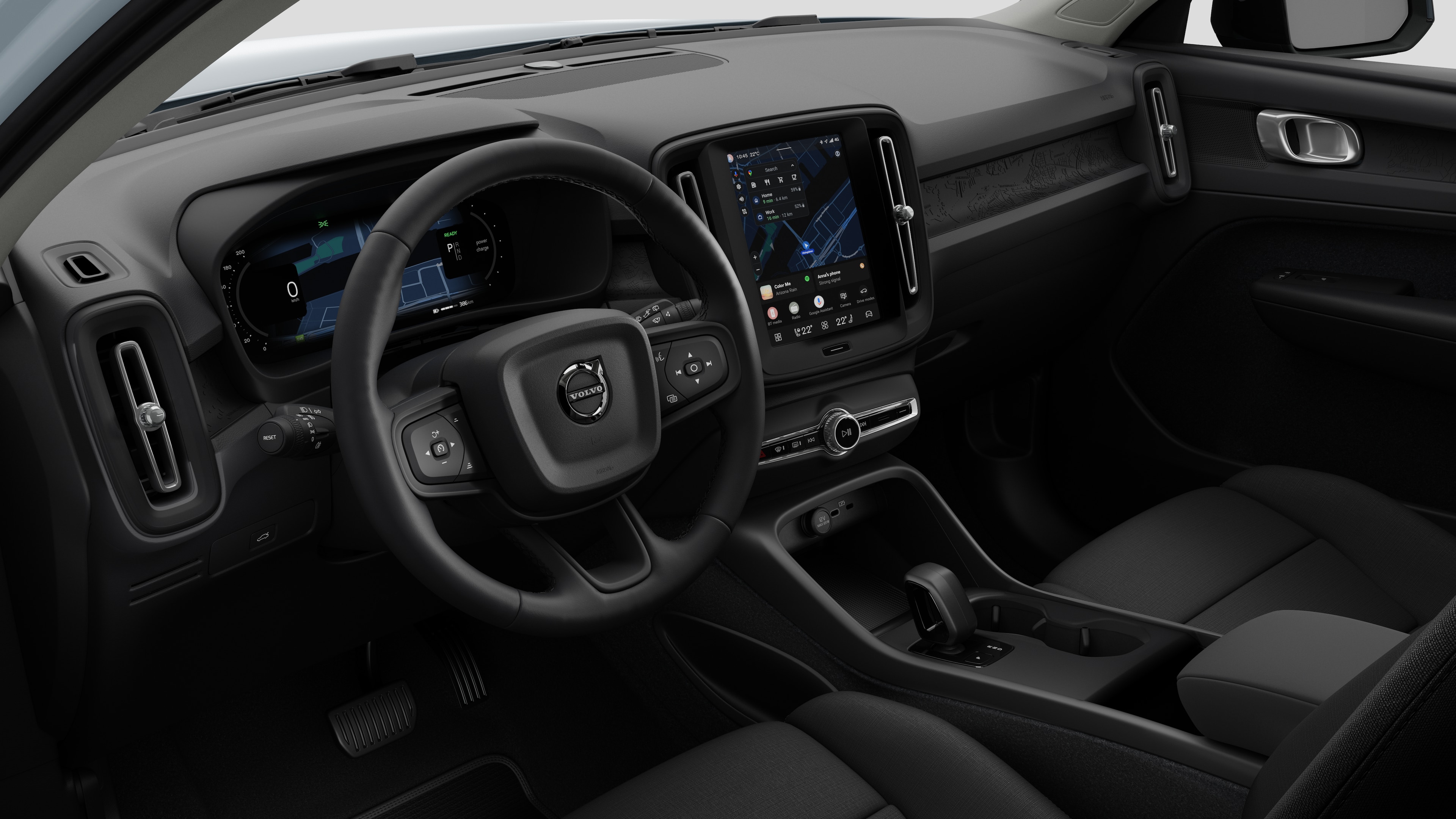 Interior view of a Volvo car showing the dashboard, steering wheel, center console, and digital display screen in a plain studio background.