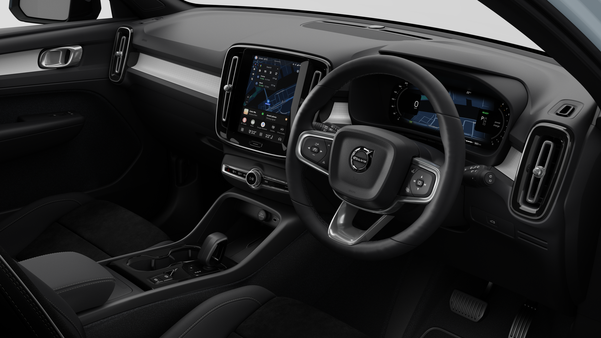 Interior view of a Volvo car showing the dashboard, steering wheel, center console, and digital display screen in a plain studio background.