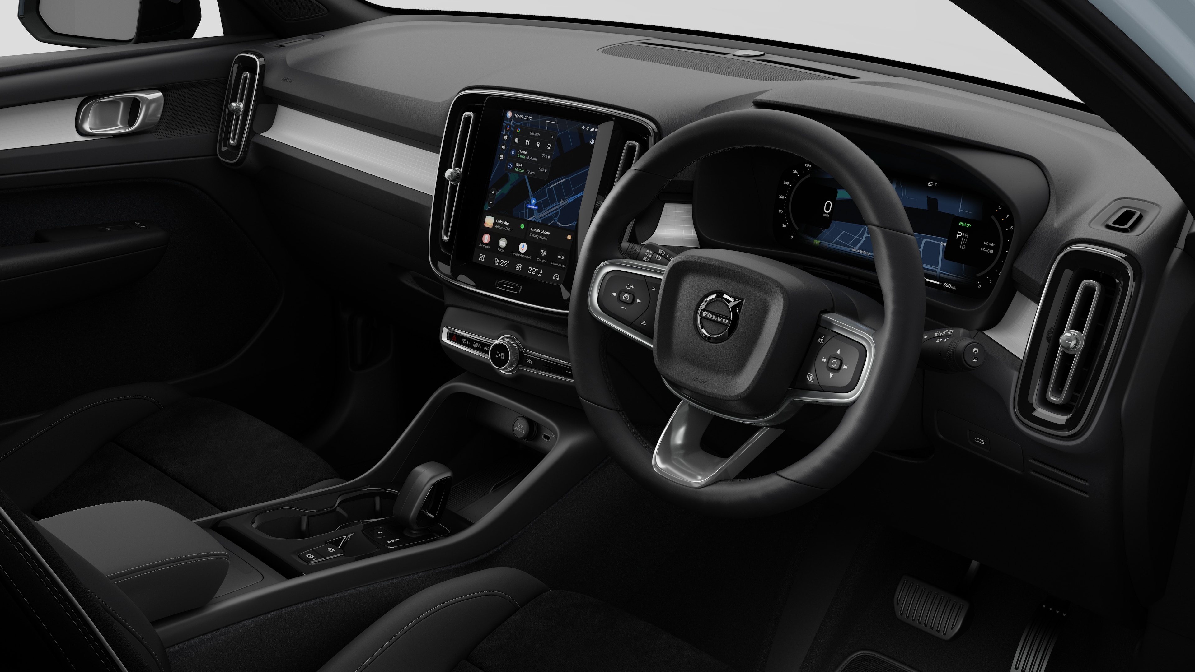 Interior view of a Volvo car showing the dashboard, steering wheel, center console, and digital display screen in a plain studio background.