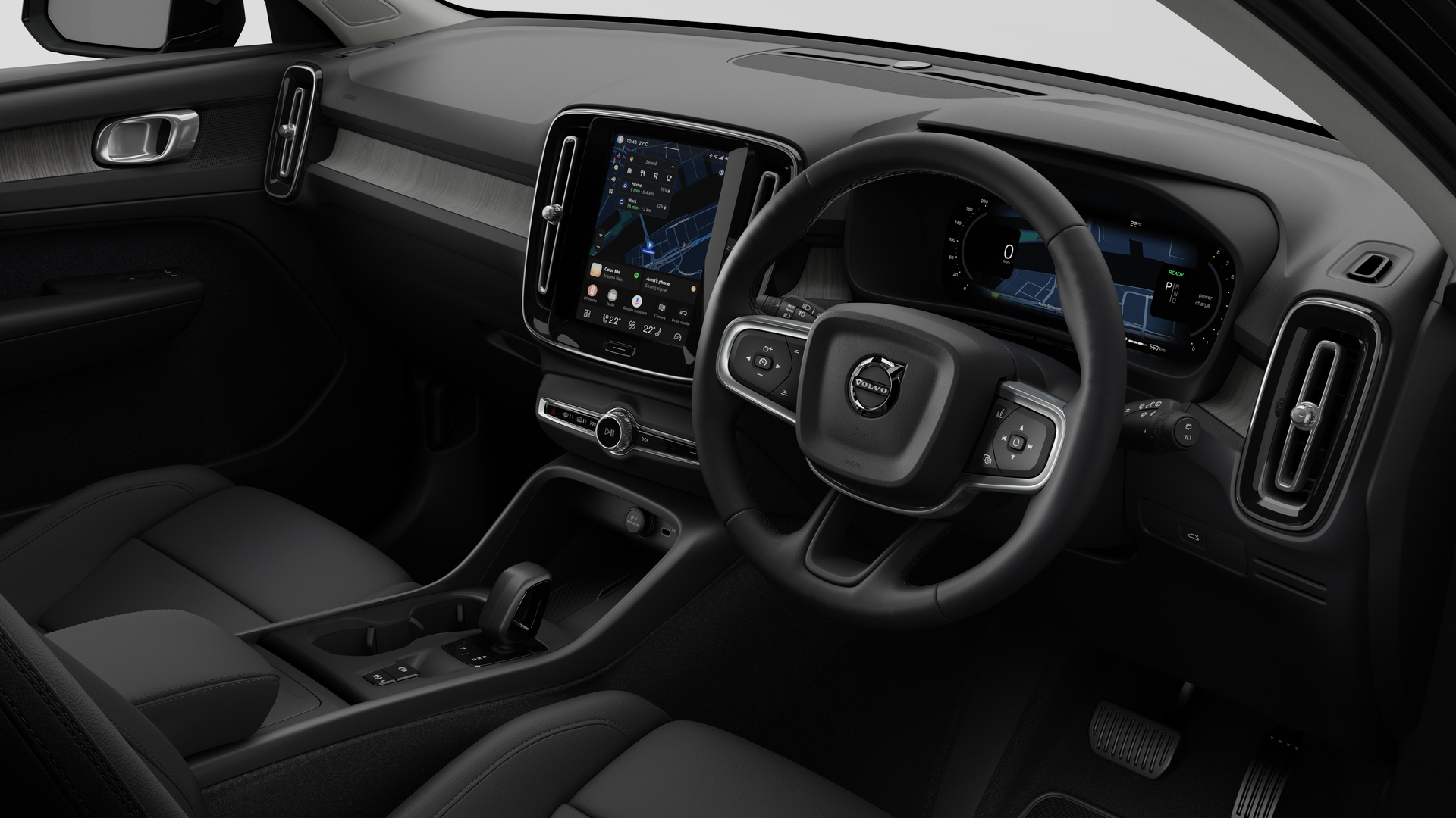Interior view of a Volvo car showing the dashboard, steering wheel, center console, and digital display screen in a plain studio background.