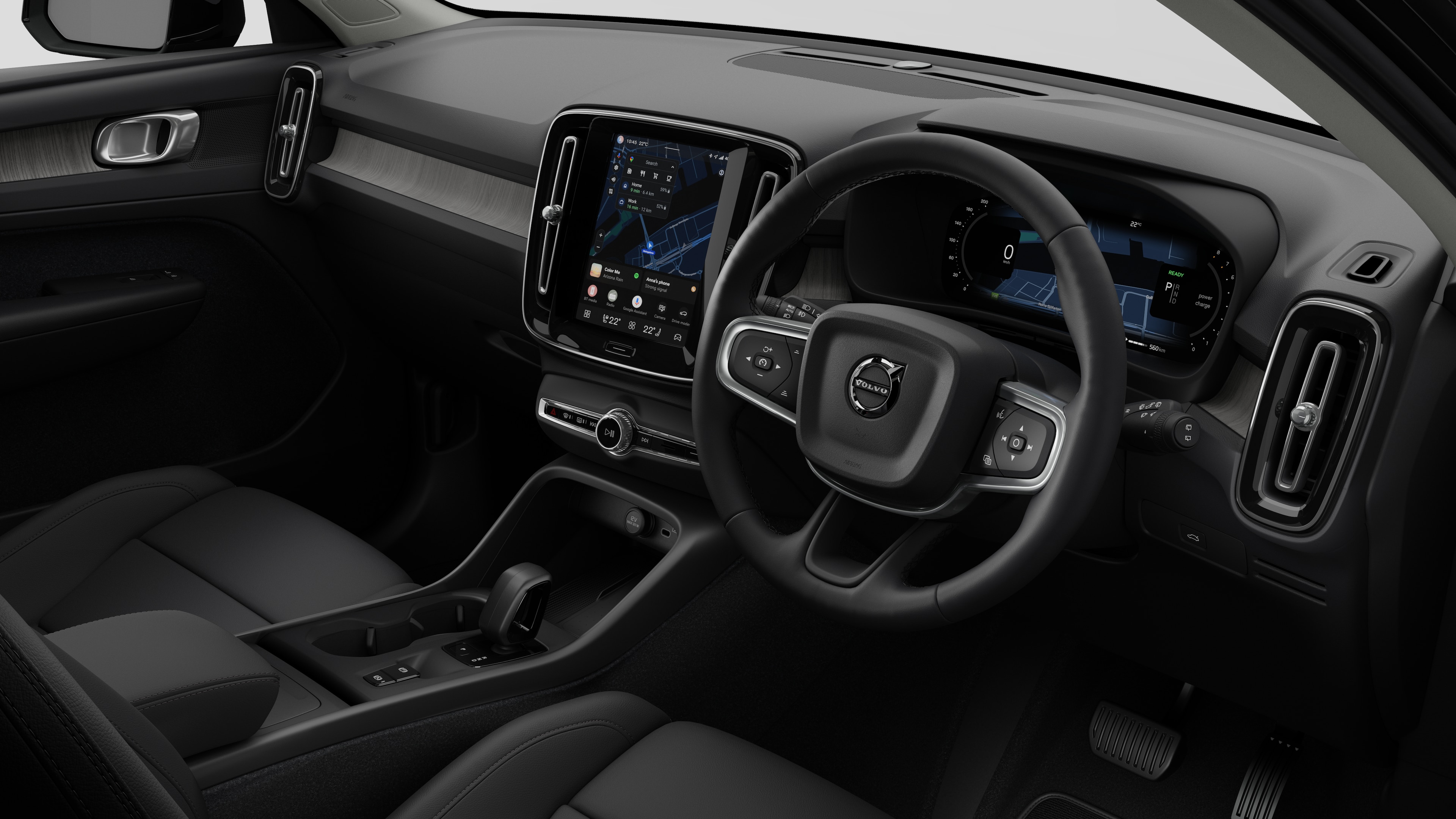 Interior view of a Volvo car showing the dashboard, steering wheel, center console, and digital display screen in a plain studio background.