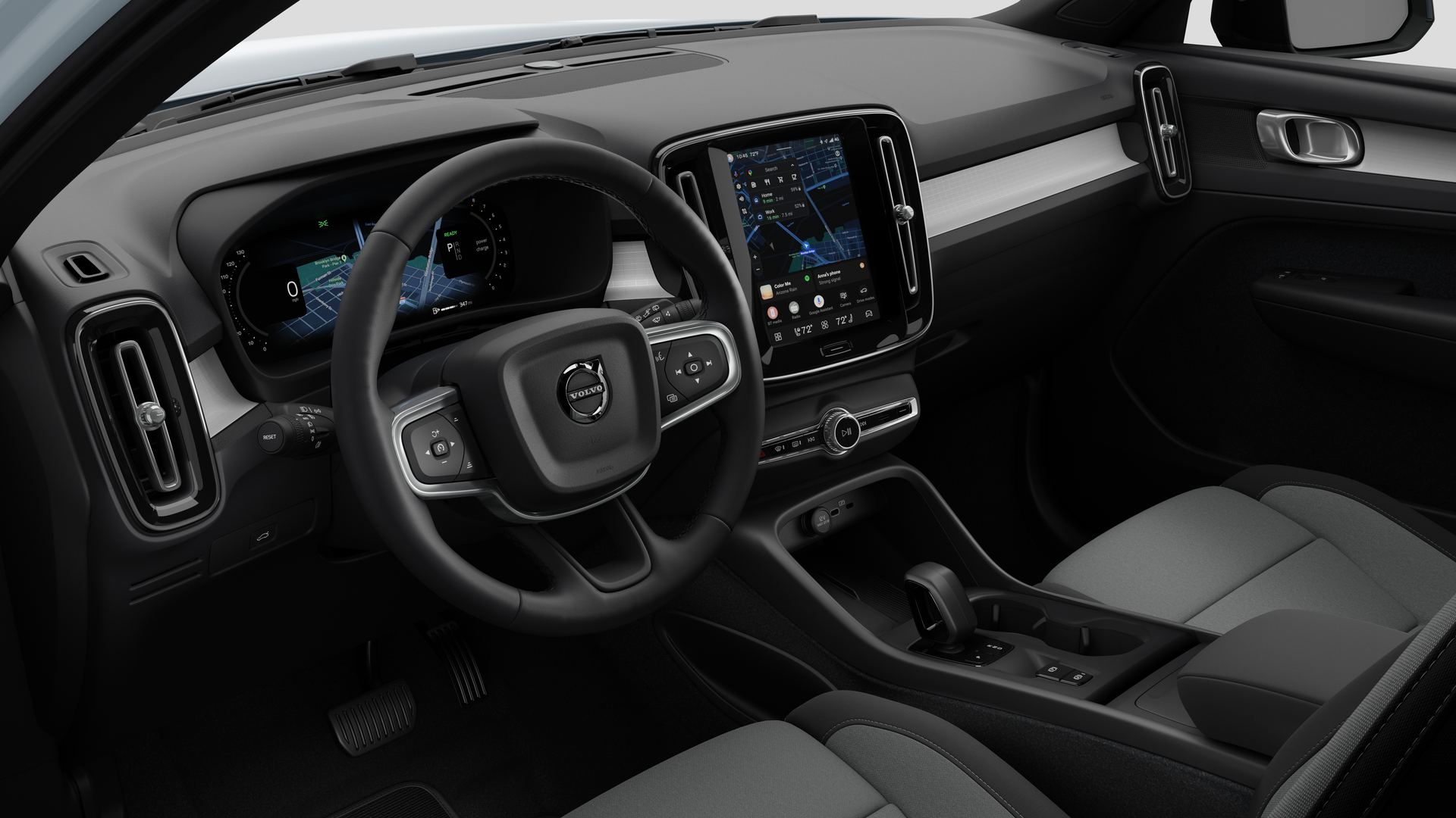 Interior view of a Volvo car showing the dashboard, steering wheel, center console, and digital display screen in a plain studio background.