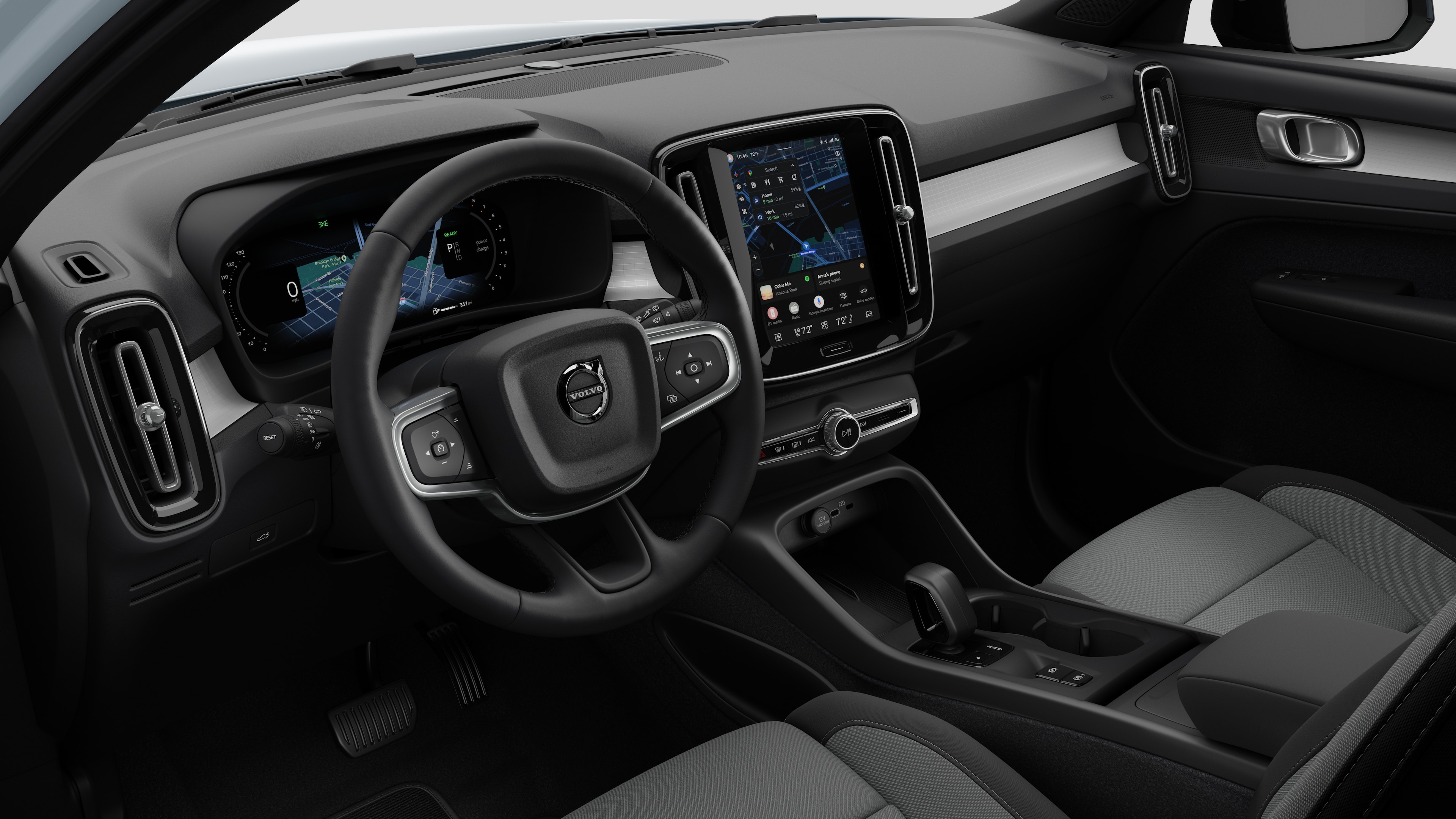Interior view of a Volvo car showing the dashboard, steering wheel, center console, and digital display screen in a plain studio background.