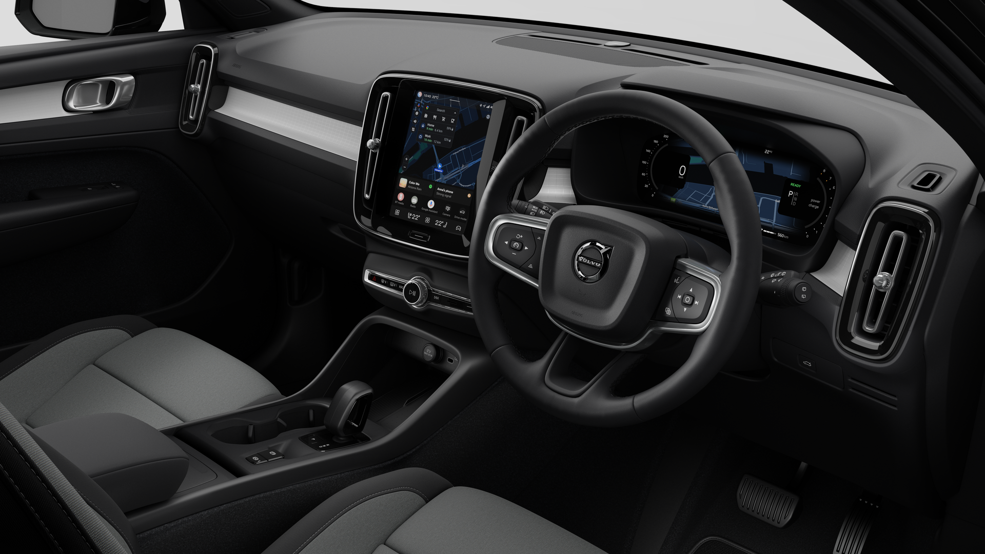Interior view of a Volvo car showing the dashboard, steering wheel, center console, and digital display screen in a plain studio background.