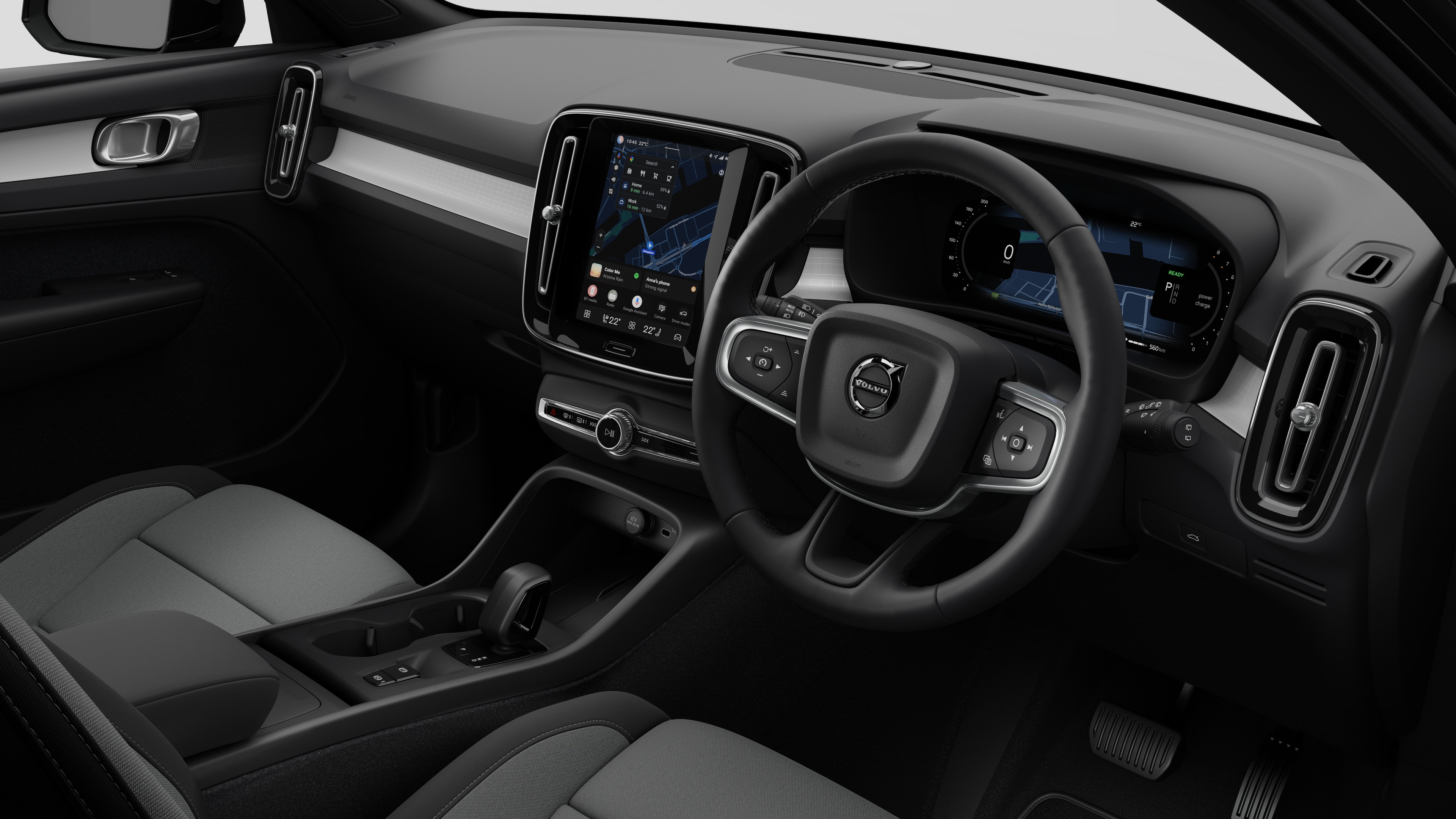 Interior view of a Volvo car showing the dashboard, steering wheel, center console, and digital display screen in a plain studio background.