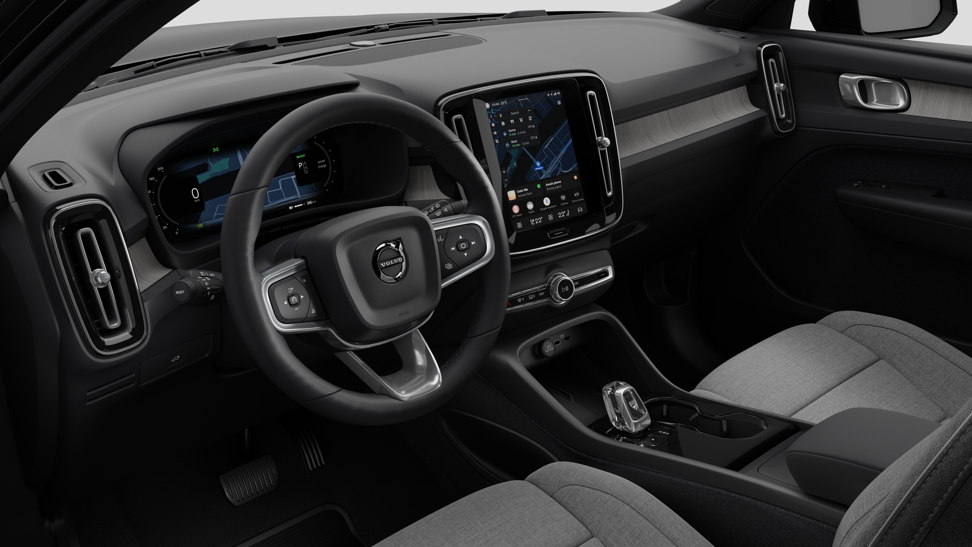 Vista interna de um carro Volvo mostrando o painel, o volante, o console central e a tela digital em um plano de fundo de estúdio simples.