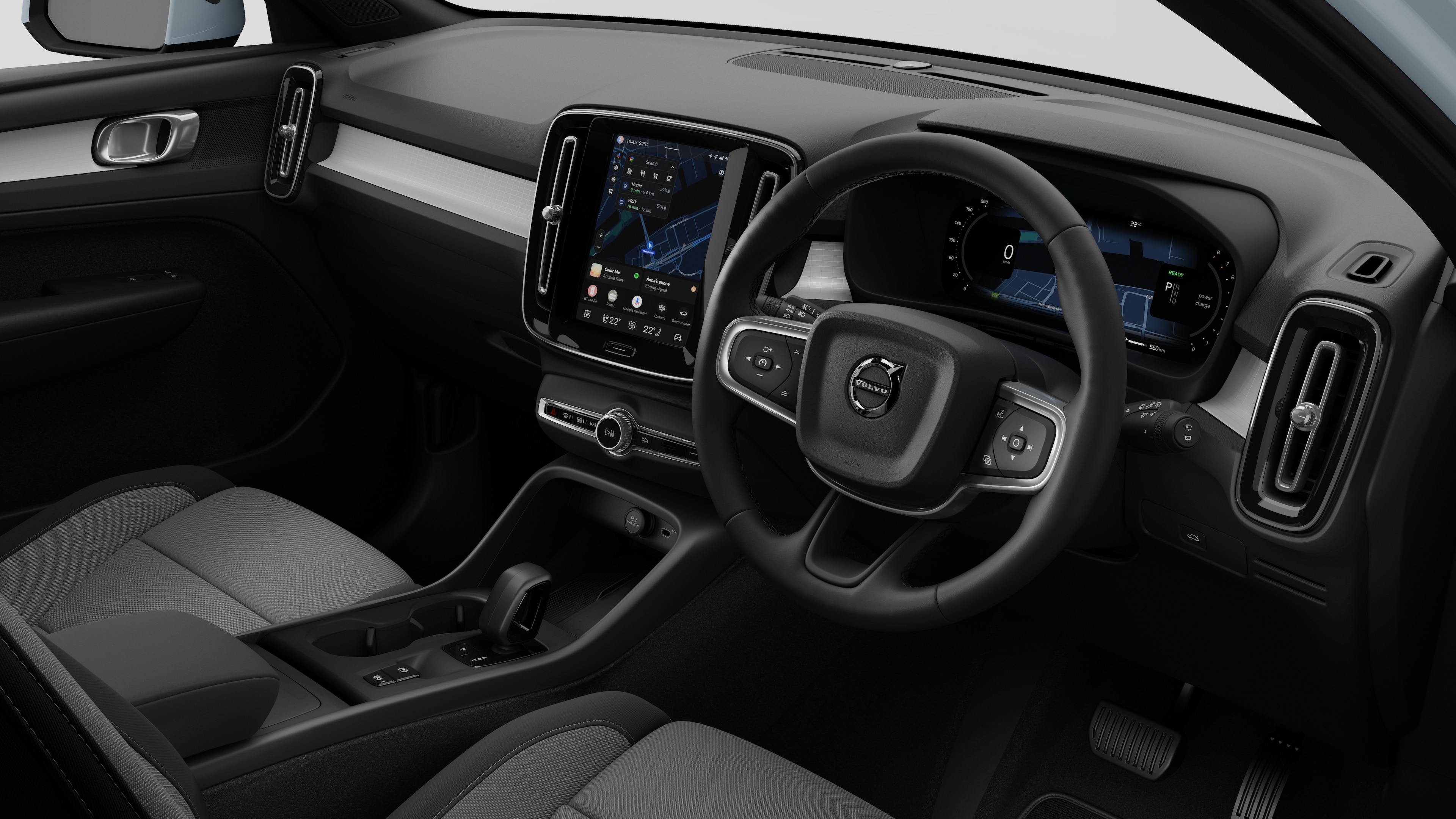 Interior view of a Volvo car showing the dashboard, steering wheel, center console, and digital display screen in a plain studio background.
