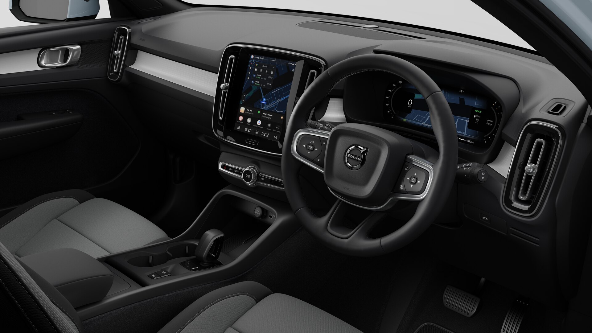 Interior view of a Volvo car showing the dashboard, steering wheel, center console, and digital display screen in a plain studio background.