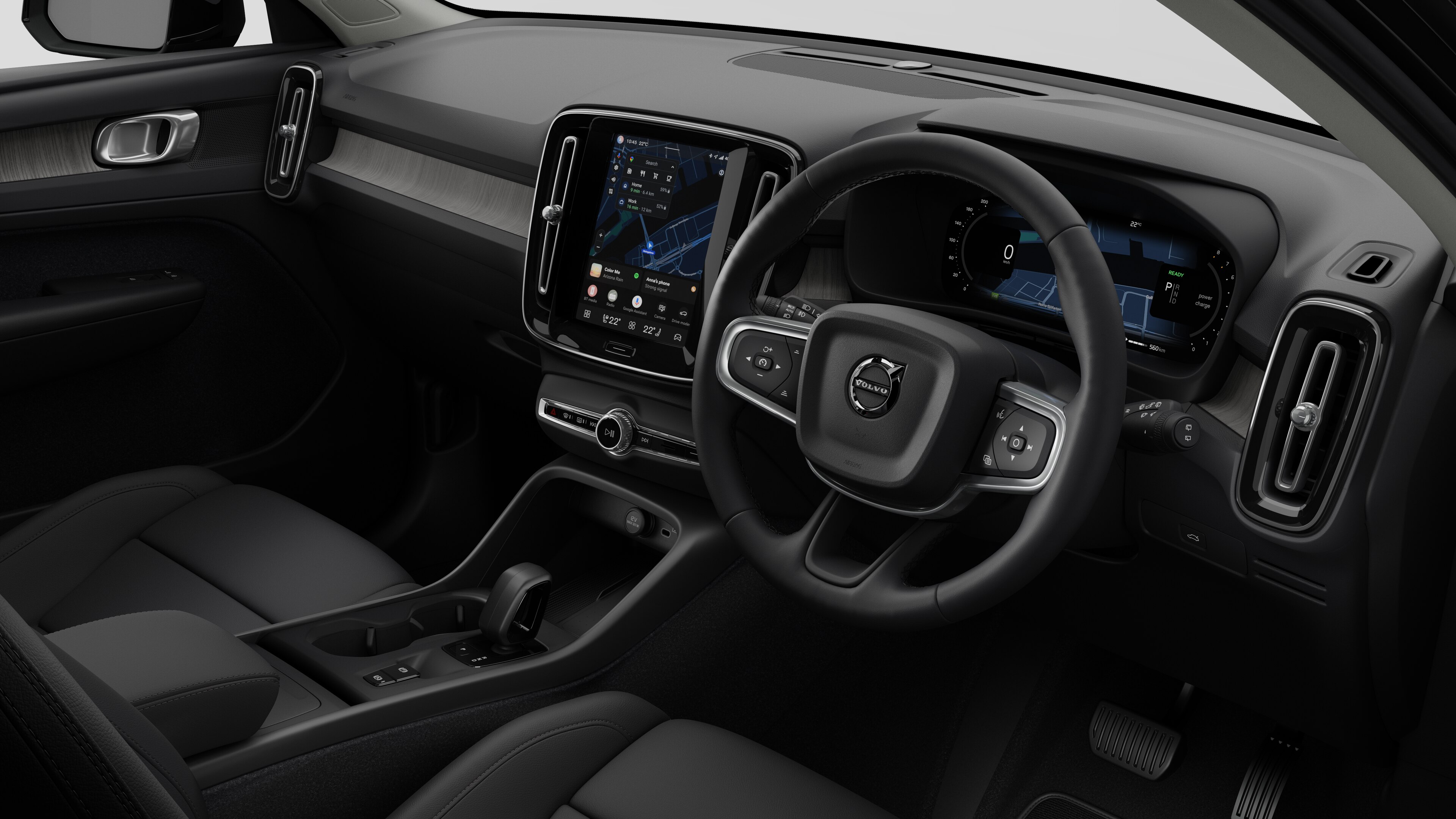 Interior view of a Volvo car showing the dashboard, steering wheel, center console, and digital display screen in a plain studio background.