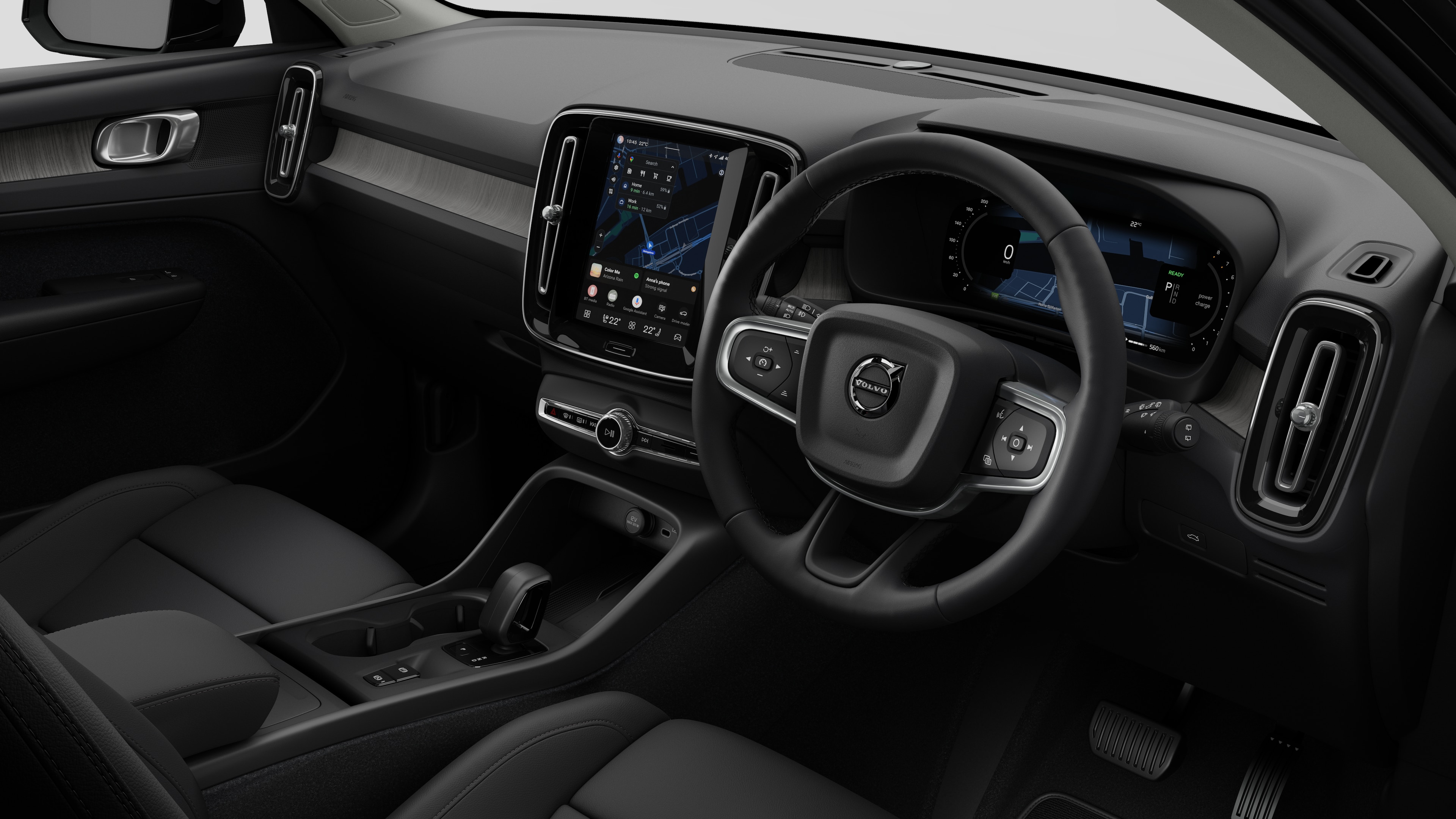 Interior view of a Volvo car showing the dashboard, steering wheel, center console, and digital display screen in a plain studio background.