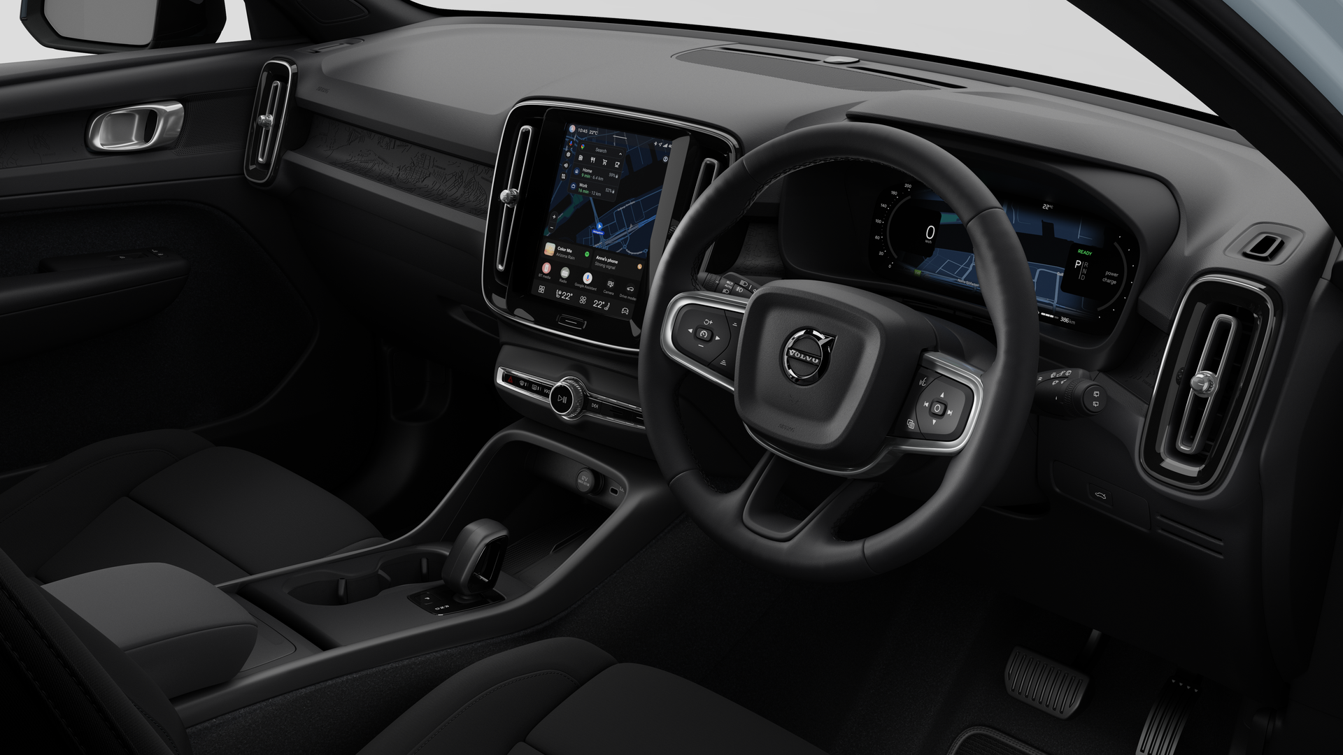 Interior view of a Volvo car showing the dashboard, steering wheel, center console, and digital display screen in a plain studio background.