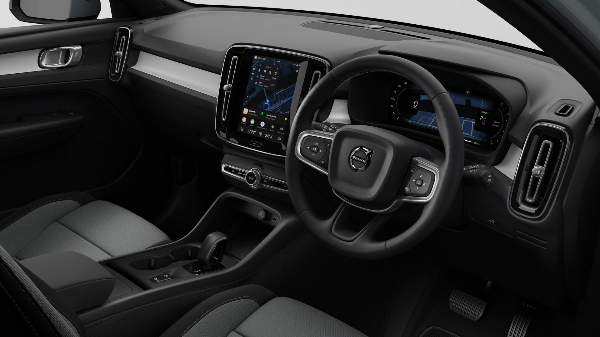 Interior view of a Volvo car showing the dashboard, steering wheel, center console, and digital display screen in a plain studio background.