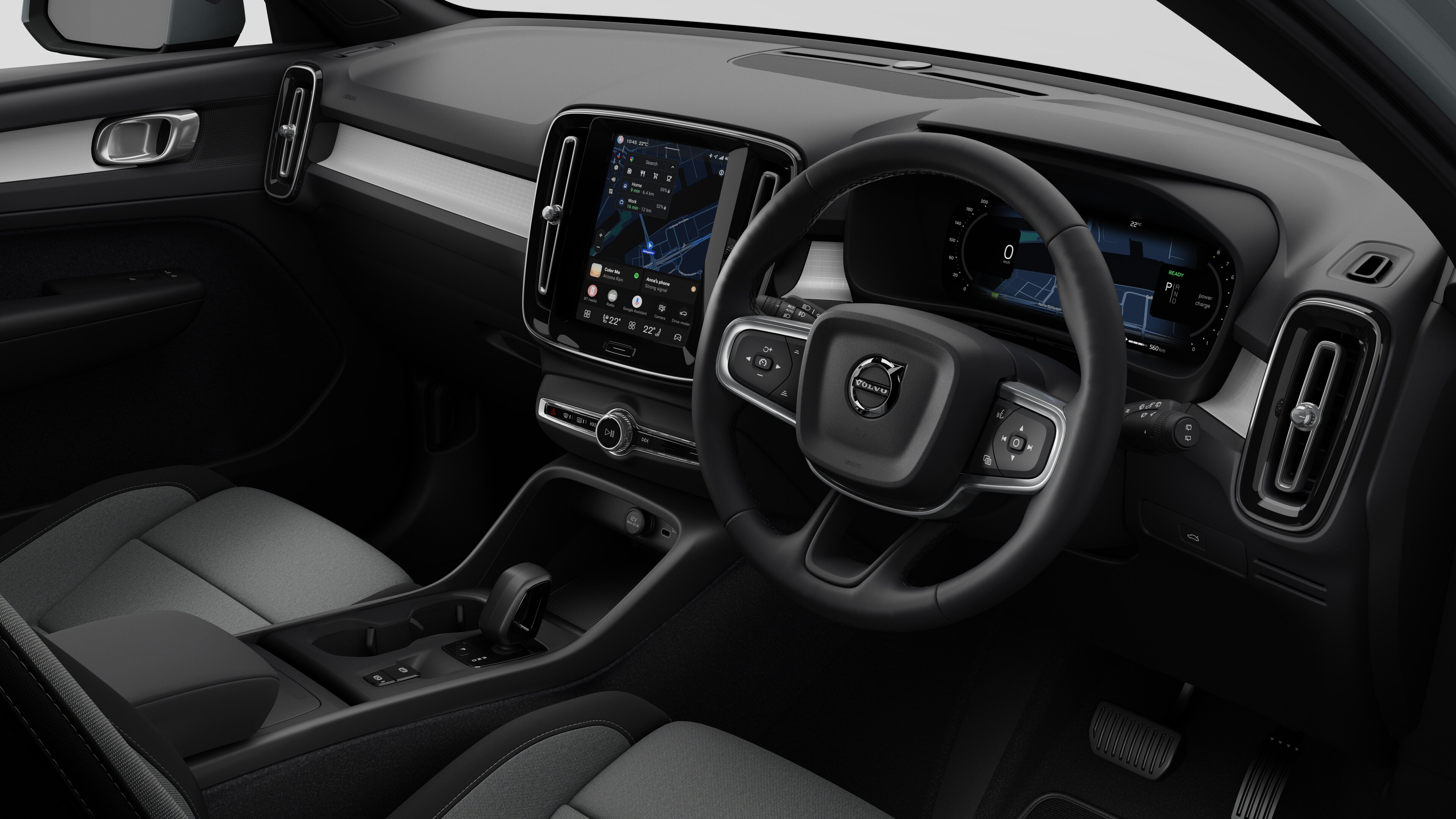 Interior view of a Volvo car showing the dashboard, steering wheel, center console, and digital display screen in a plain studio background.