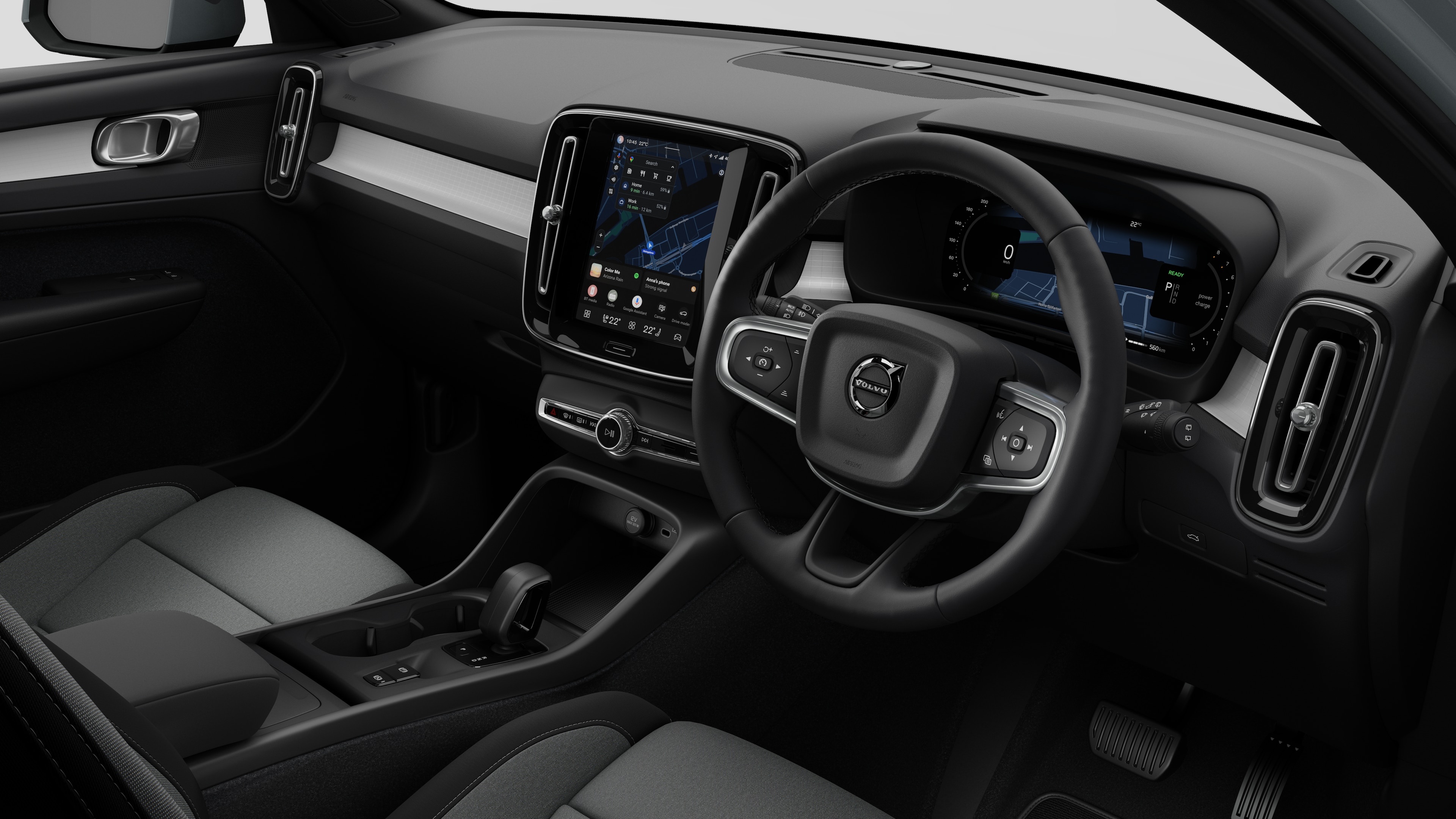 Interior view of a Volvo car showing the dashboard, steering wheel, center console, and digital display screen in a plain studio background.