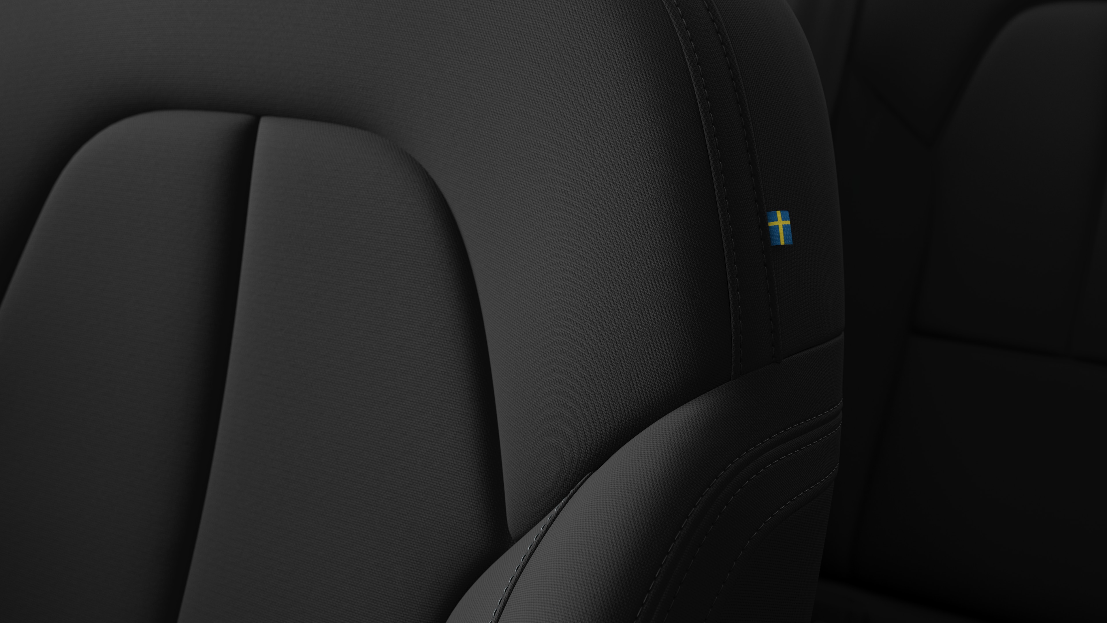 Närbild av Volvo Cars interiör, sätesdetalj som visar sömmar och en liten svensk flagga.
