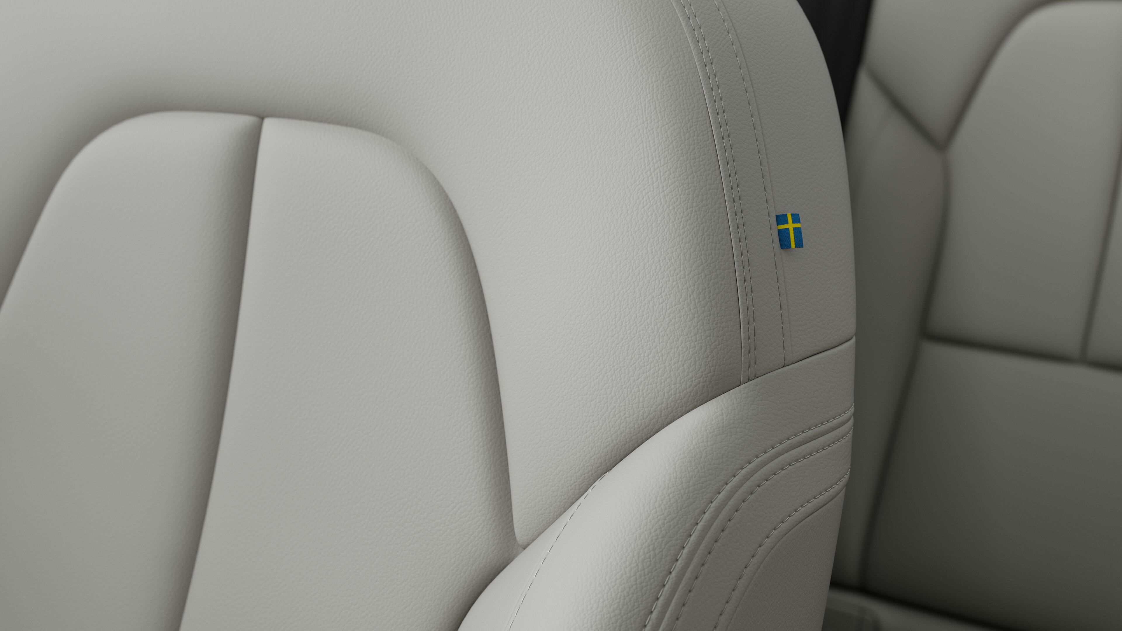 Close-up of Volvo car interior seat detail showing stitching and a small Swedish flag tag.