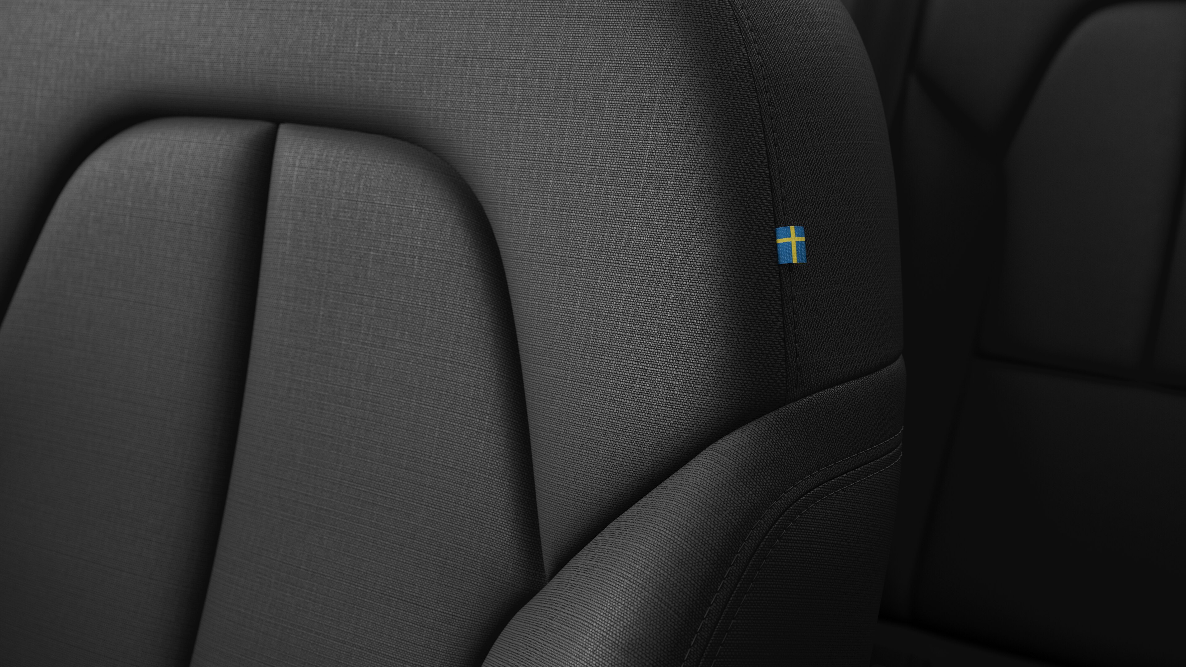 Nahaufnahme eines Innenraums eines Volvo Fahrzeugs mit Nähten und einem kleinen Etikett mit schwedischer Flagge.