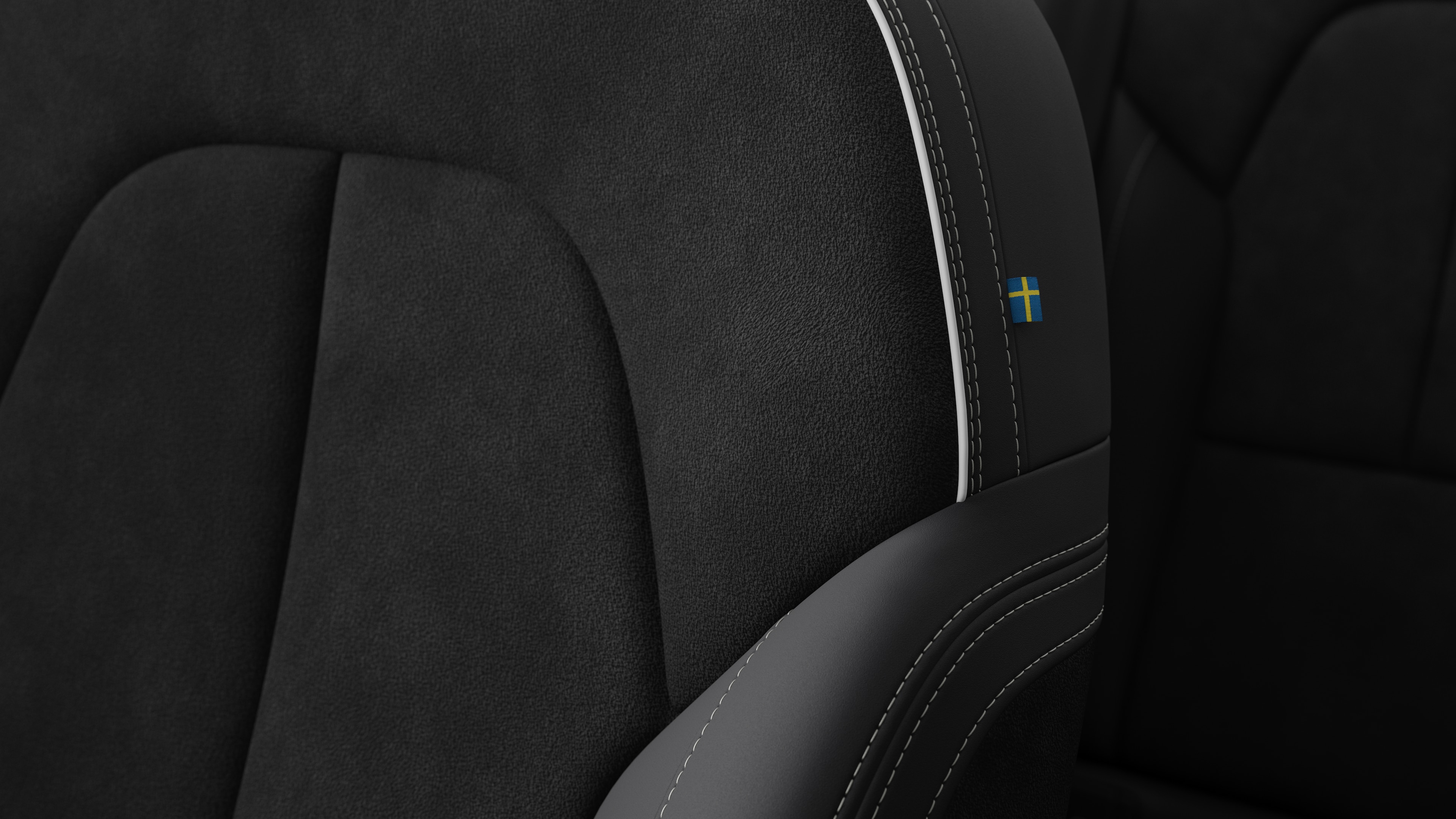 Primer plano del detalle del asiento interior del vehículo Volvo que muestra costuras y una pequeña etiqueta con la bandera sueca.