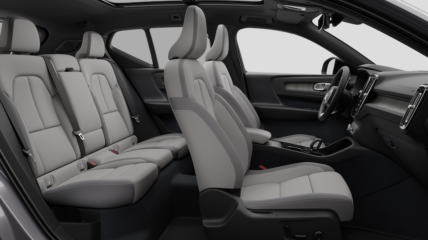 Volvo -auton sisätilojen sivunäkymä, jossa näkyy etuistuimet, takamatkustajan istuimet, ohjauspyörä, kojelauta ja keskikonsoli studiotaustaa vasten.