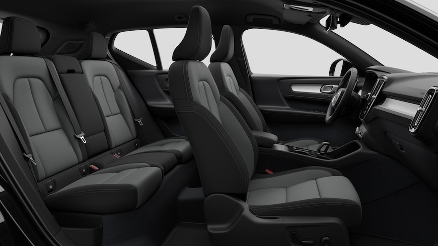 Vista lateral del interior de un coche Volvo en la que se ven los asientos delanteros, los asientos del pasajero trasero, el volante, el salpicadero y la consola central, sobre un fondo de estudio liso.