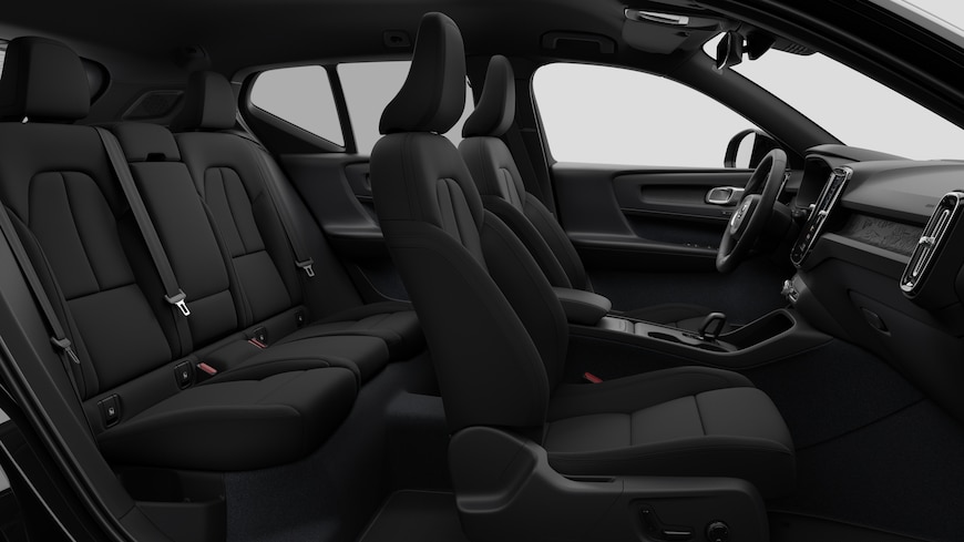 Seitenansicht des Innenraums eines Volvo mit Vordersitzen, Beifahrersitzen, Lenkrad, Armaturenbrett und Mittelkonsole vor einem schlichten Studiohintergrund.