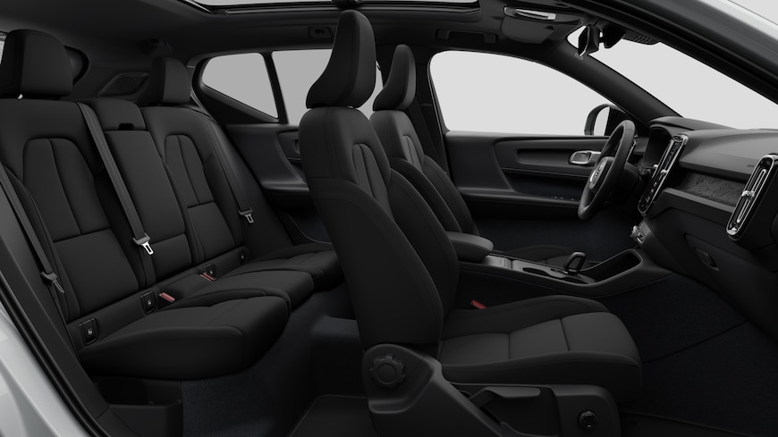 Seitenansicht des Innenraums eines Volvo mit Vordersitzen, Beifahrersitzen, Lenkrad, Armaturenbrett und Mittelkonsole vor einem schlichten Studiohintergrund.