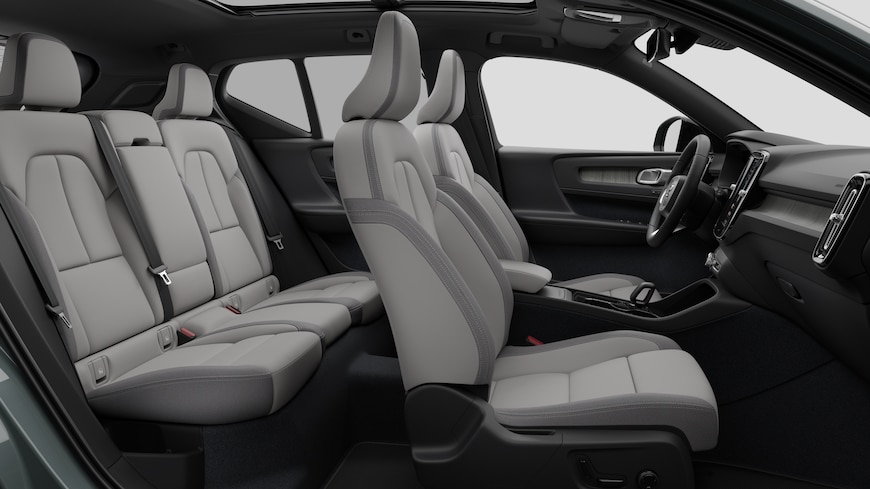 Volvo car interior side view showcasing front seats, rear passenger seats, steering wheel, dashboard, and center console, set against plain studio background.