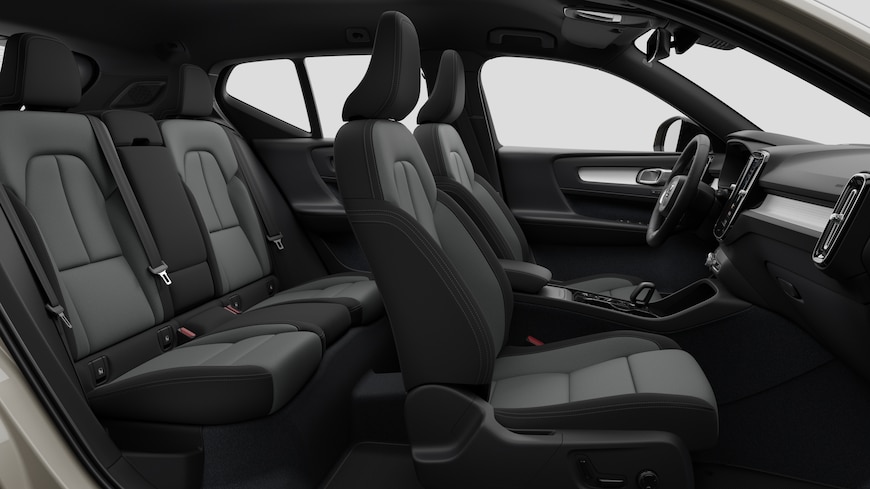 Vista lateral del interior de un coche Volvo en la que se ven los asientos delanteros, los asientos del pasajero trasero, el volante, el salpicadero y la consola central, sobre un fondo de estudio liso.