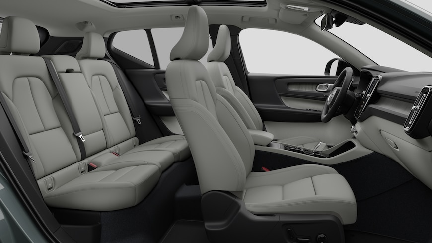 Volvo car interior side view showcasing front seats, rear passenger seats, steering wheel, dashboard, and center console, set against plain studio background.